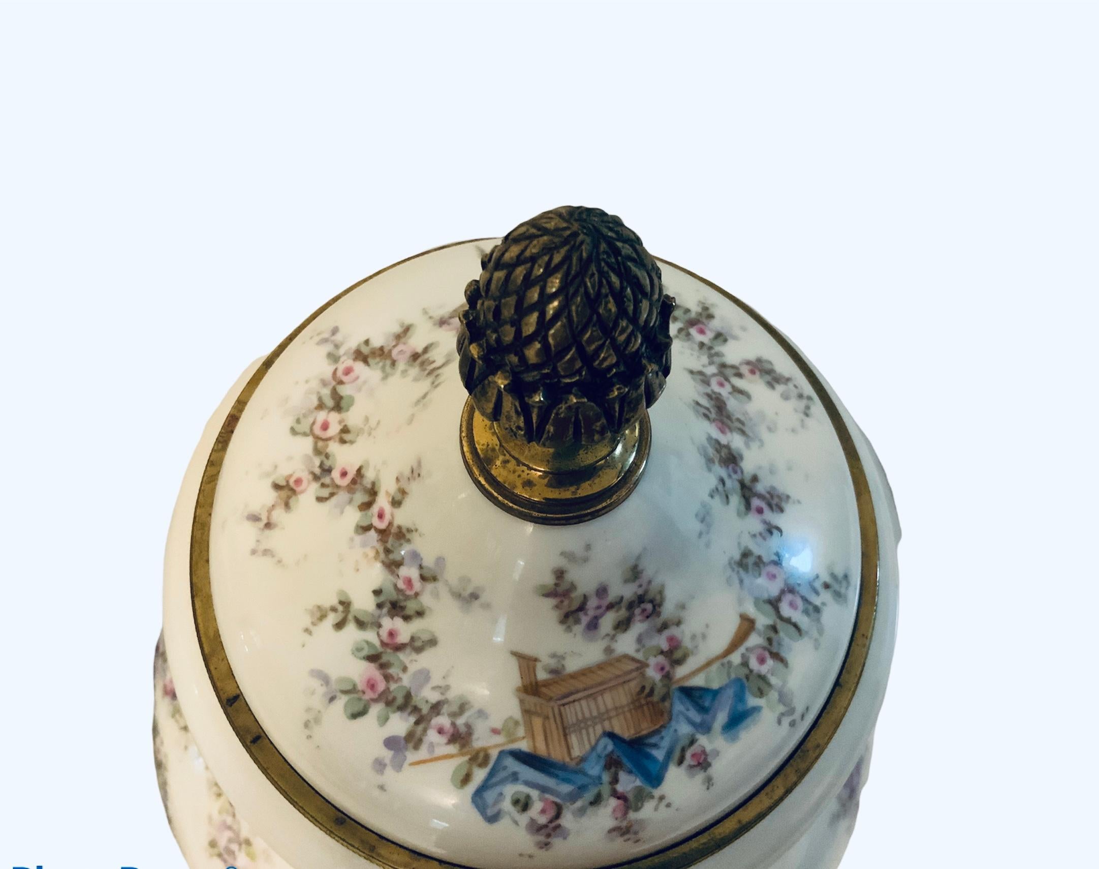 This is a large and heavy Sevres French bronze mounted porcelain lidded urn. It is hand painted in a white background. It depicts three winged cherubs that are seated in a large rock ( one is holding a feather pen, the other one is thoughtful while