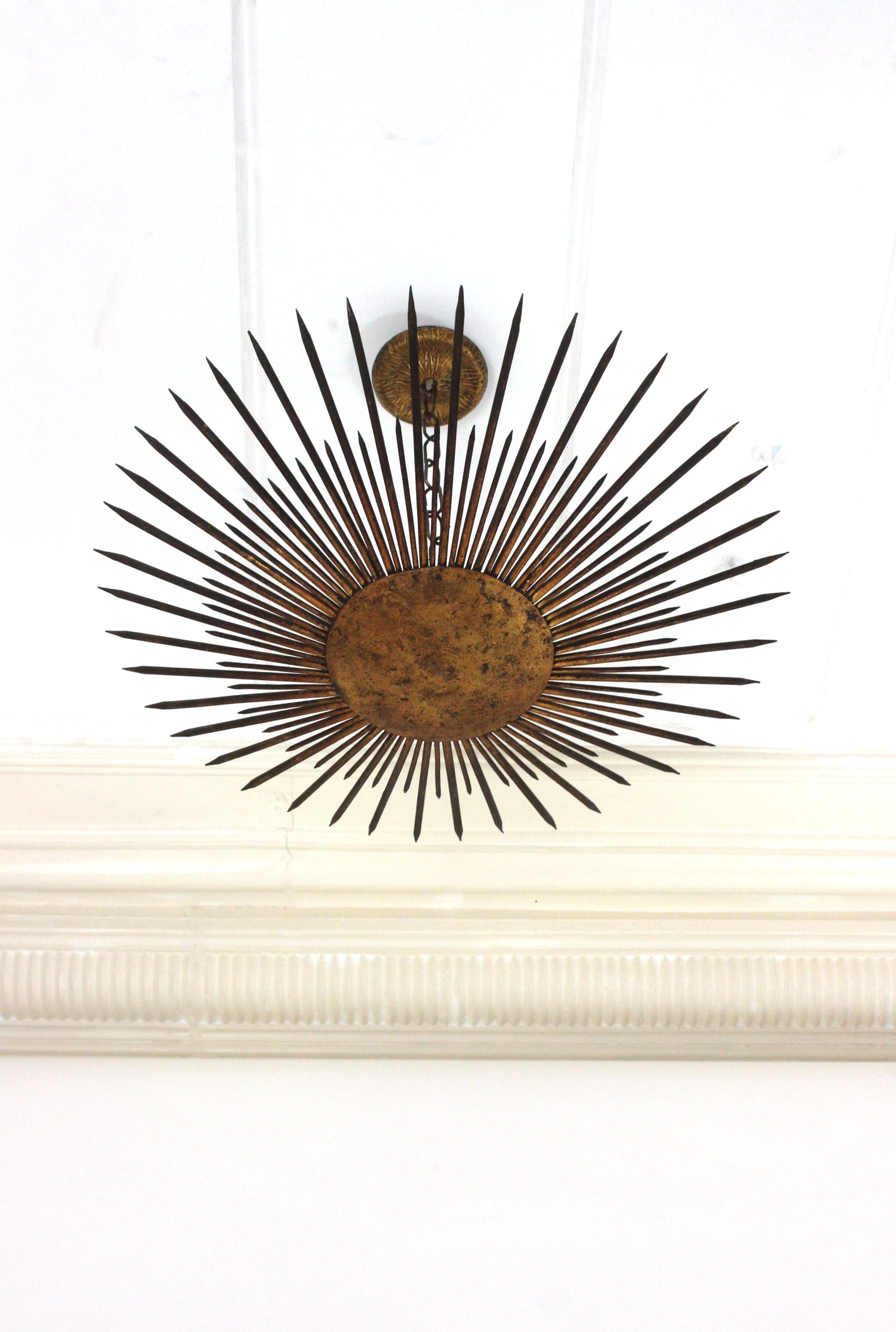 French Modern Neoclassical Sunburst Chandelier / Light Fixture with Spikes Detail,  France, 1940s
This stunning hand-hammered gilt iron sunburst ceiling light was manufactured at the Art Deco Period. It has accents in transition to Brutalist style.