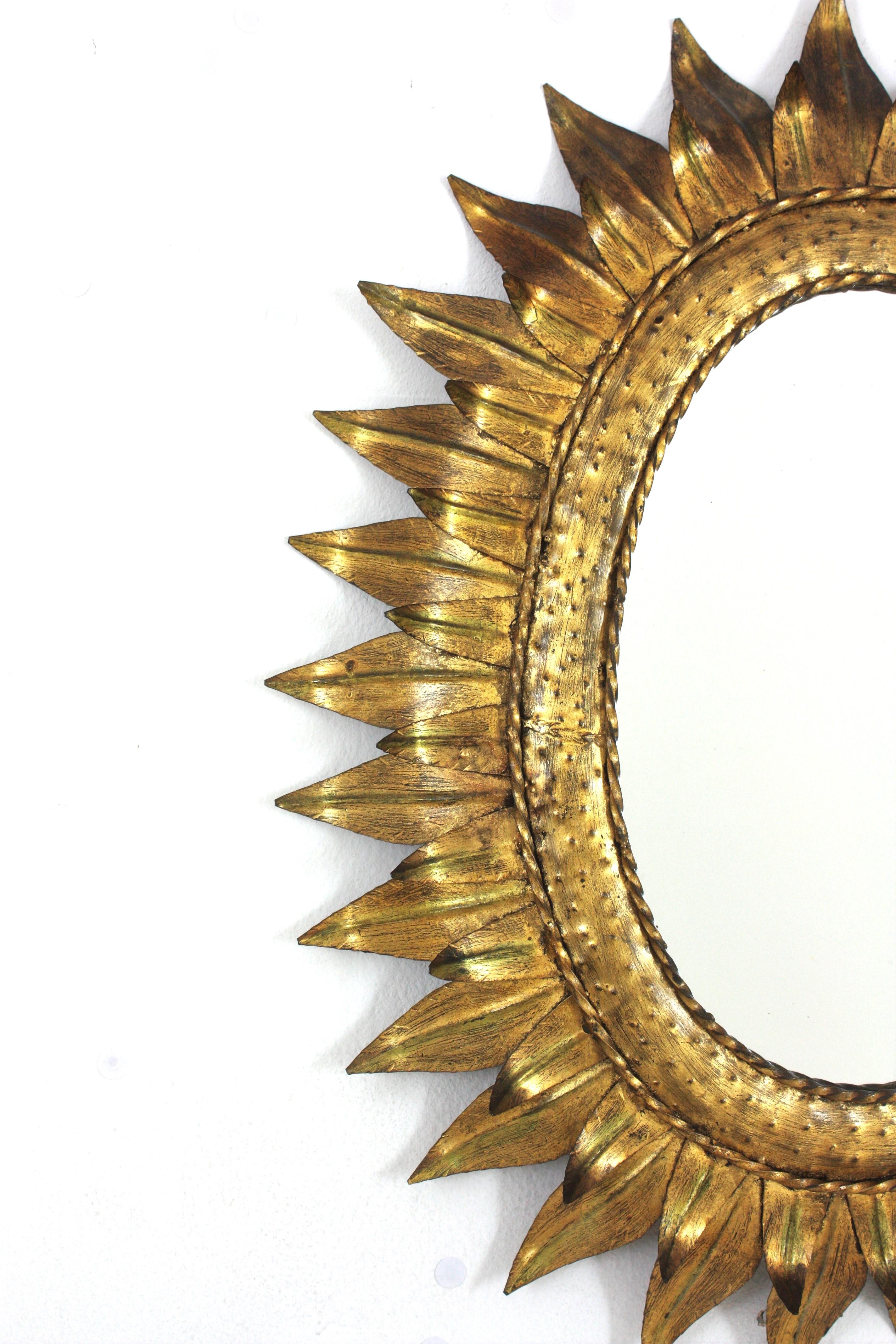 Gran espejo oval francés Sunburst de metal dorado con marco de doble hoja, años 50 Forjado en venta