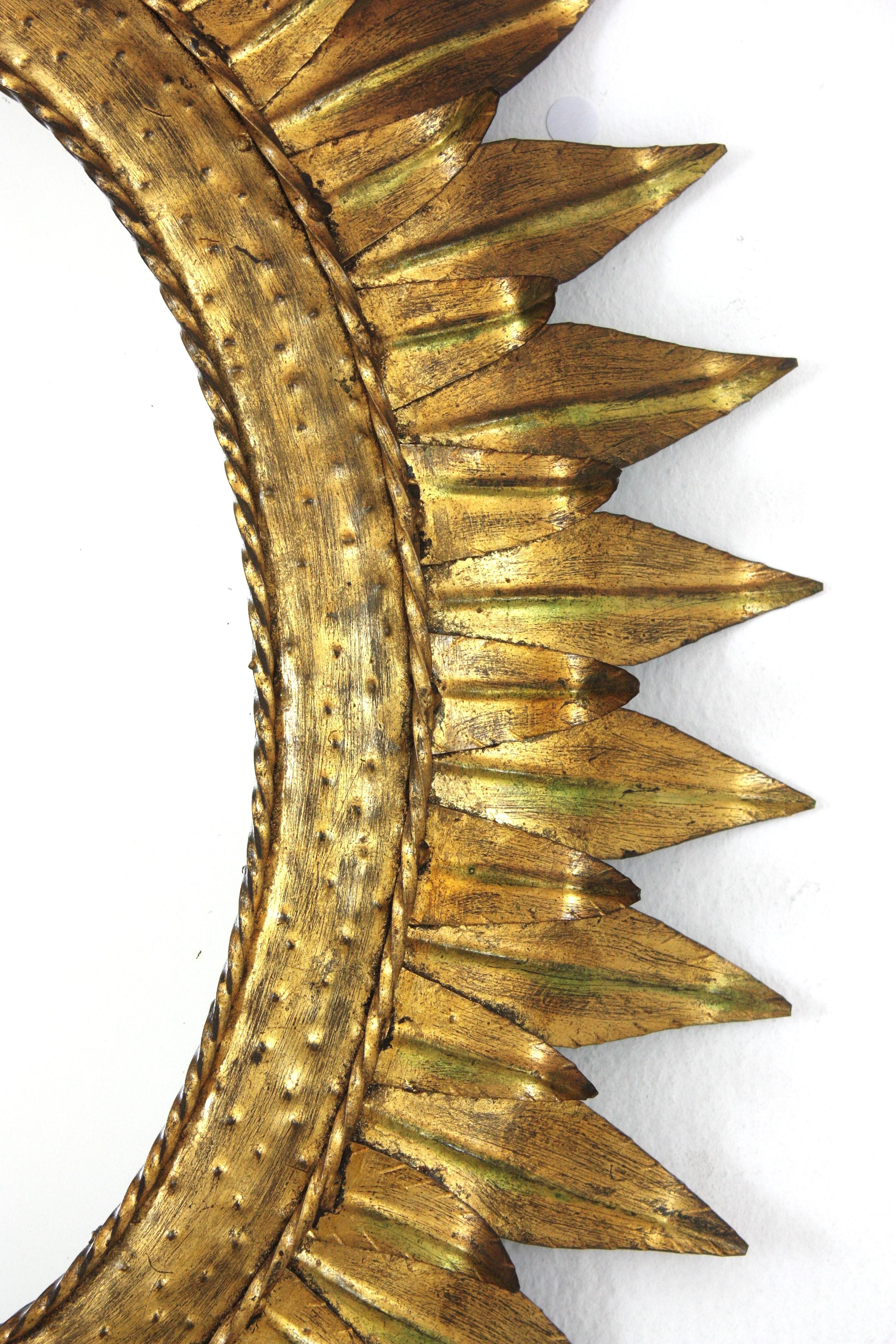 Gran espejo oval francés Sunburst de metal dorado con marco de doble hoja, años 50 siglo XX en venta