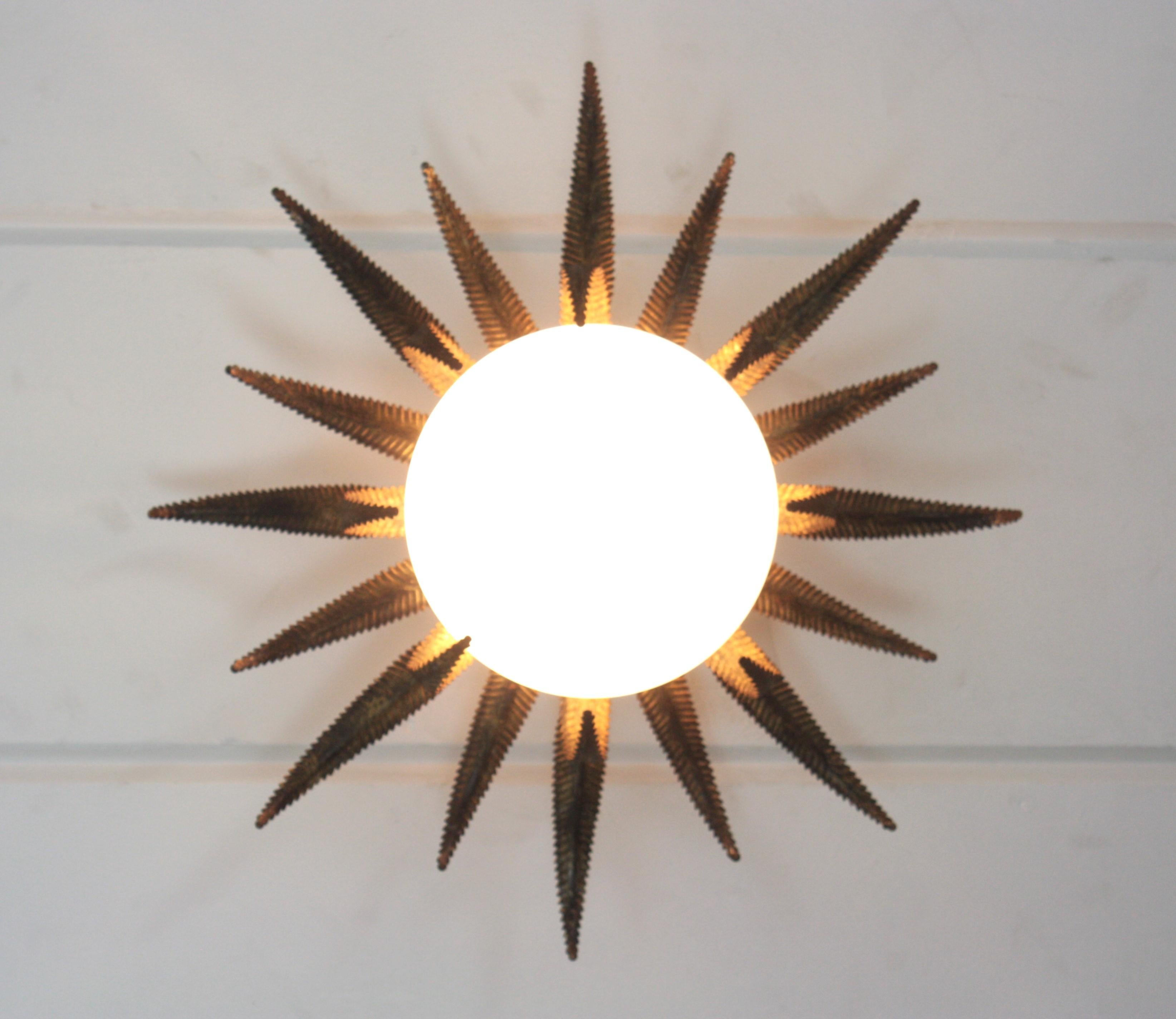 Remarquable encastrement français en métal doré et verre de lait, années 1950
Ce plafonnier à étoiles en forme de soleil est doté d'une construction qui attire l'attention. La base en fer doré patiné et en forme de soleil ou d'étoile porte un