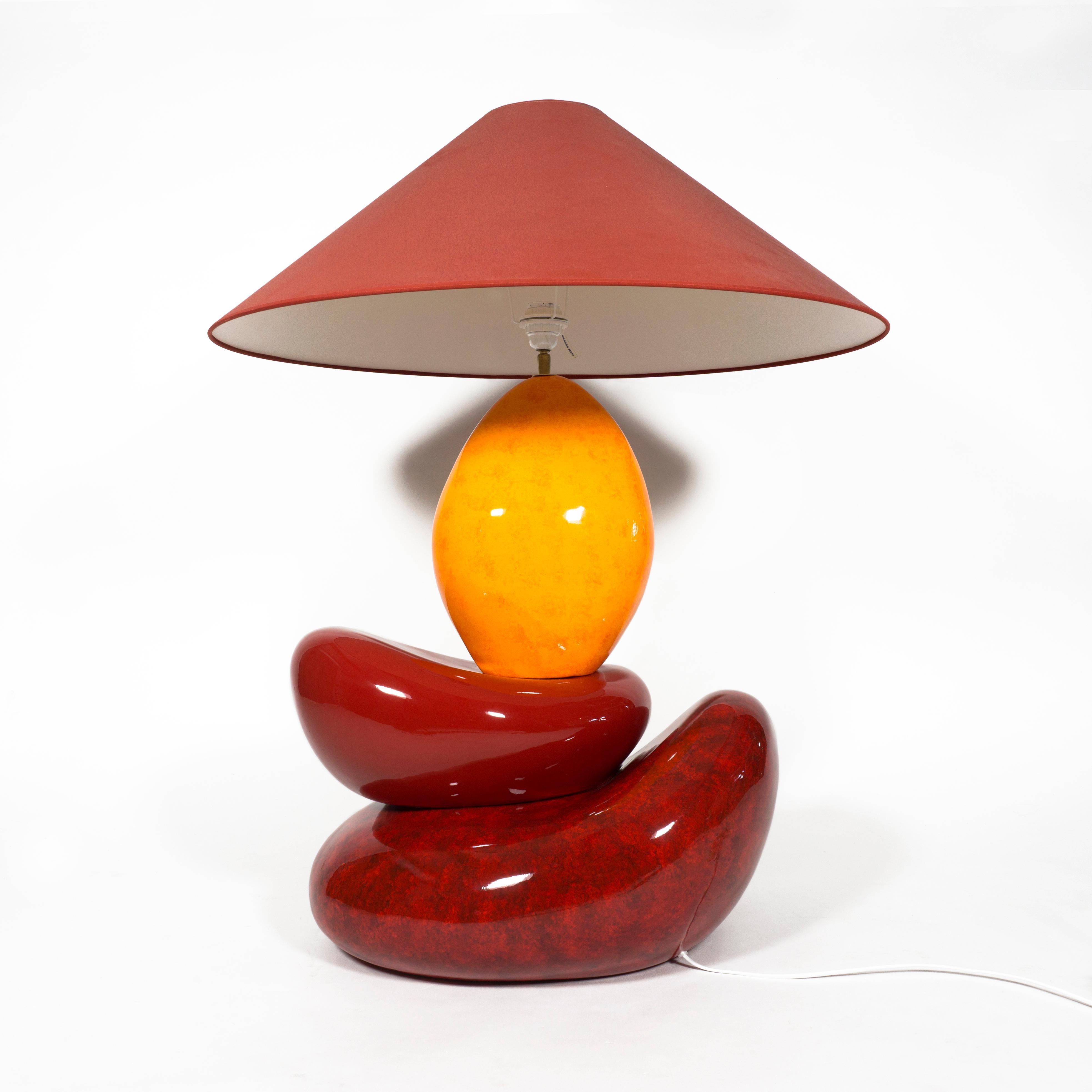 Superbe lampe de table en céramique émaillée rouge et jaune de François Châtain, datant de la fin du 20e siècle.
Cette lampe de table française, énorme et colorée, a une base impressionnante. Les boules de céramique en forme de galets et empilées de