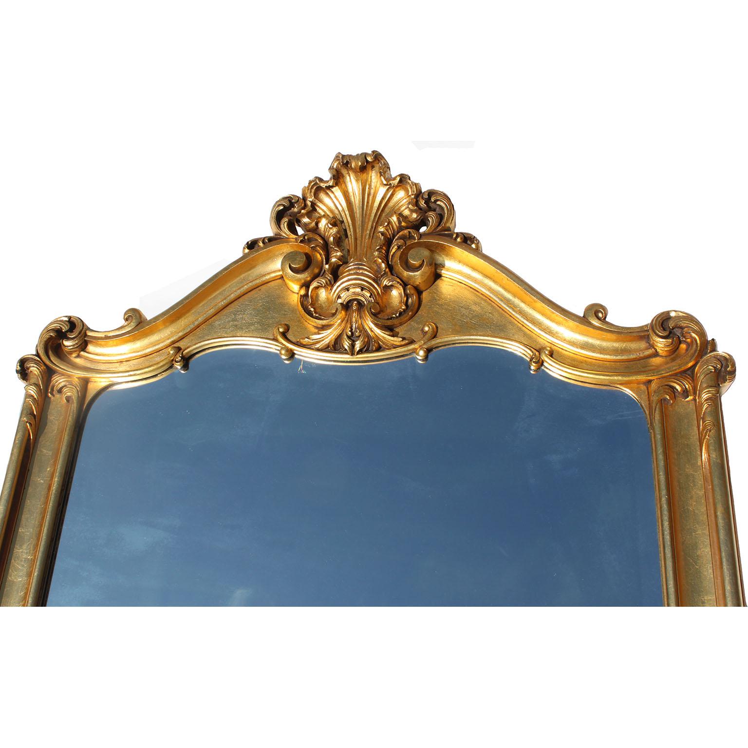 Grande specchio francese di transizione in stile Belle Époque Luigi XIV/XV in legno dorato e intagliato. La cornice in legno dorato, ben intagliata, è coronata da uno stemma floreale, acanto e volute affiancato da angoli volute, la parte inferiore è