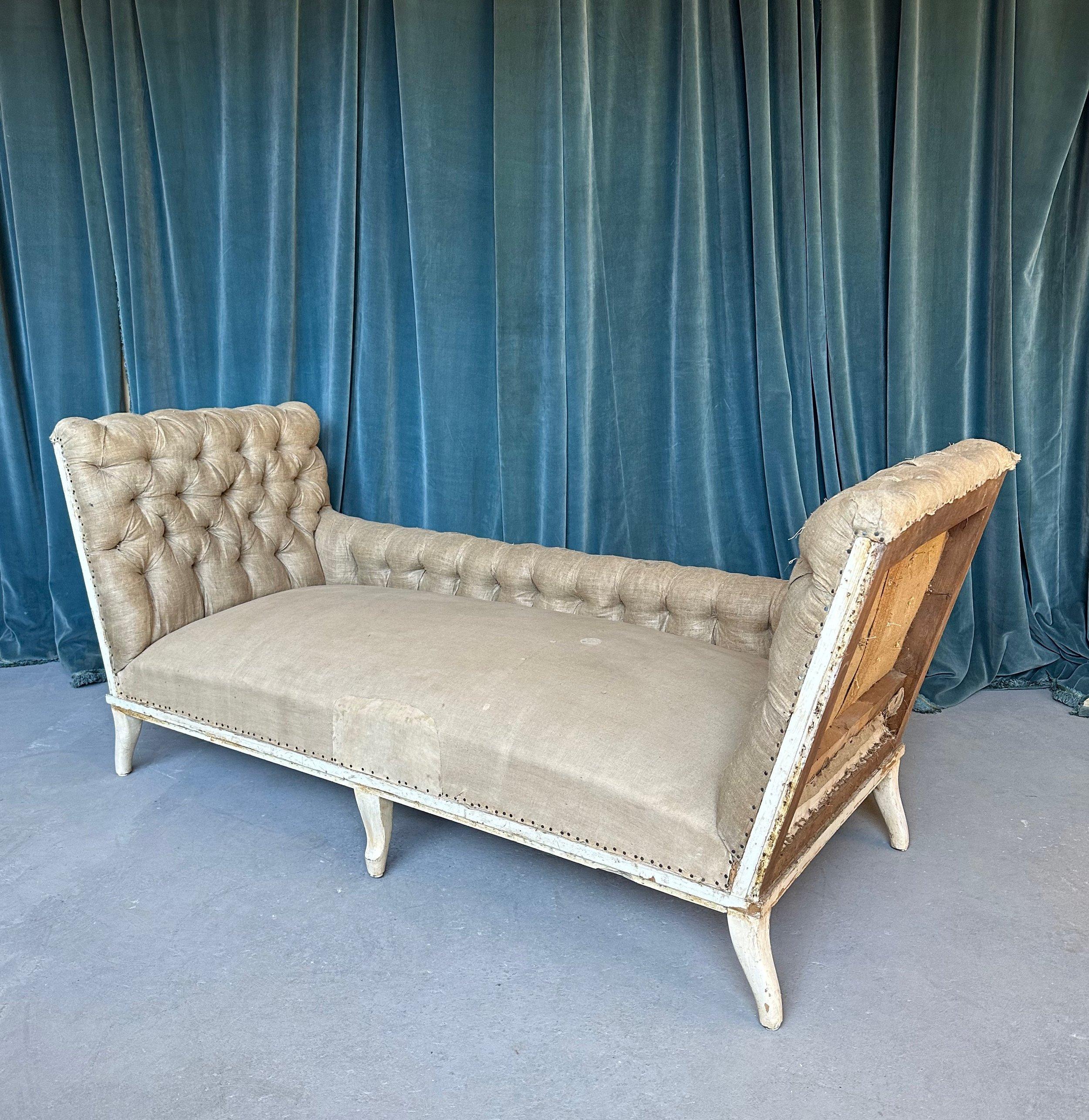 This unique and stately large scale French 19th century Napoleon III sofa features gracefully extended arms that contrast the low back and give this sofa a distinctly elegant appeal. The back and arms are masterfully and heavily tufted - adding to