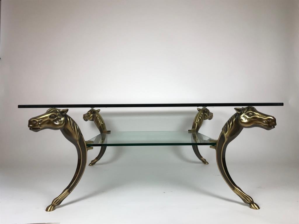 A gorgeous two-tiered bevelled glass coffee table on sculptural gilded bronze stands depicting horses.