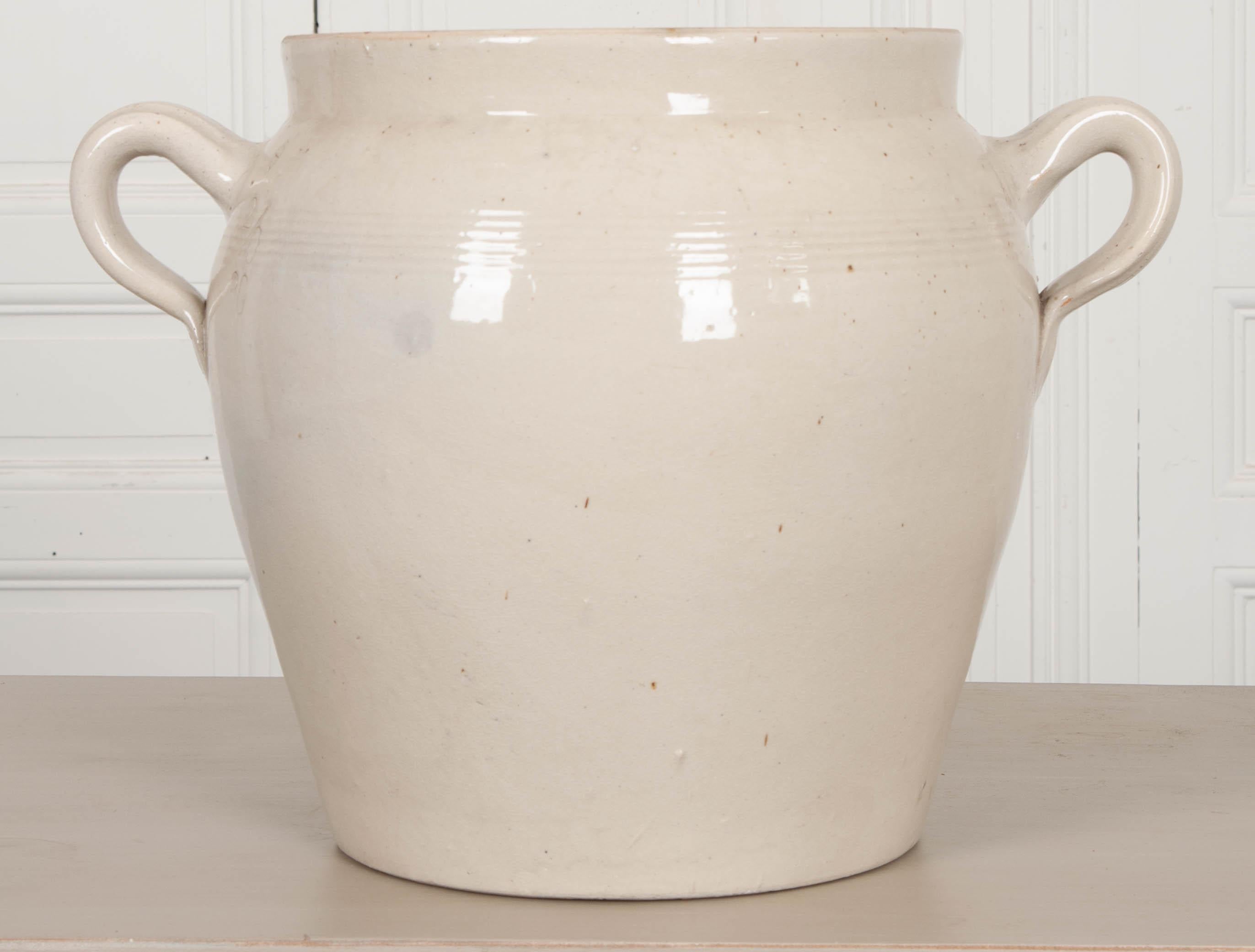 A vintage glazed earthenware crock is from France. Its looped handles make lifting the pot a little easier, and the decorative banding found between them gives it a distinct style. Every ceramic pot will differ slightly, as they are all thrown by