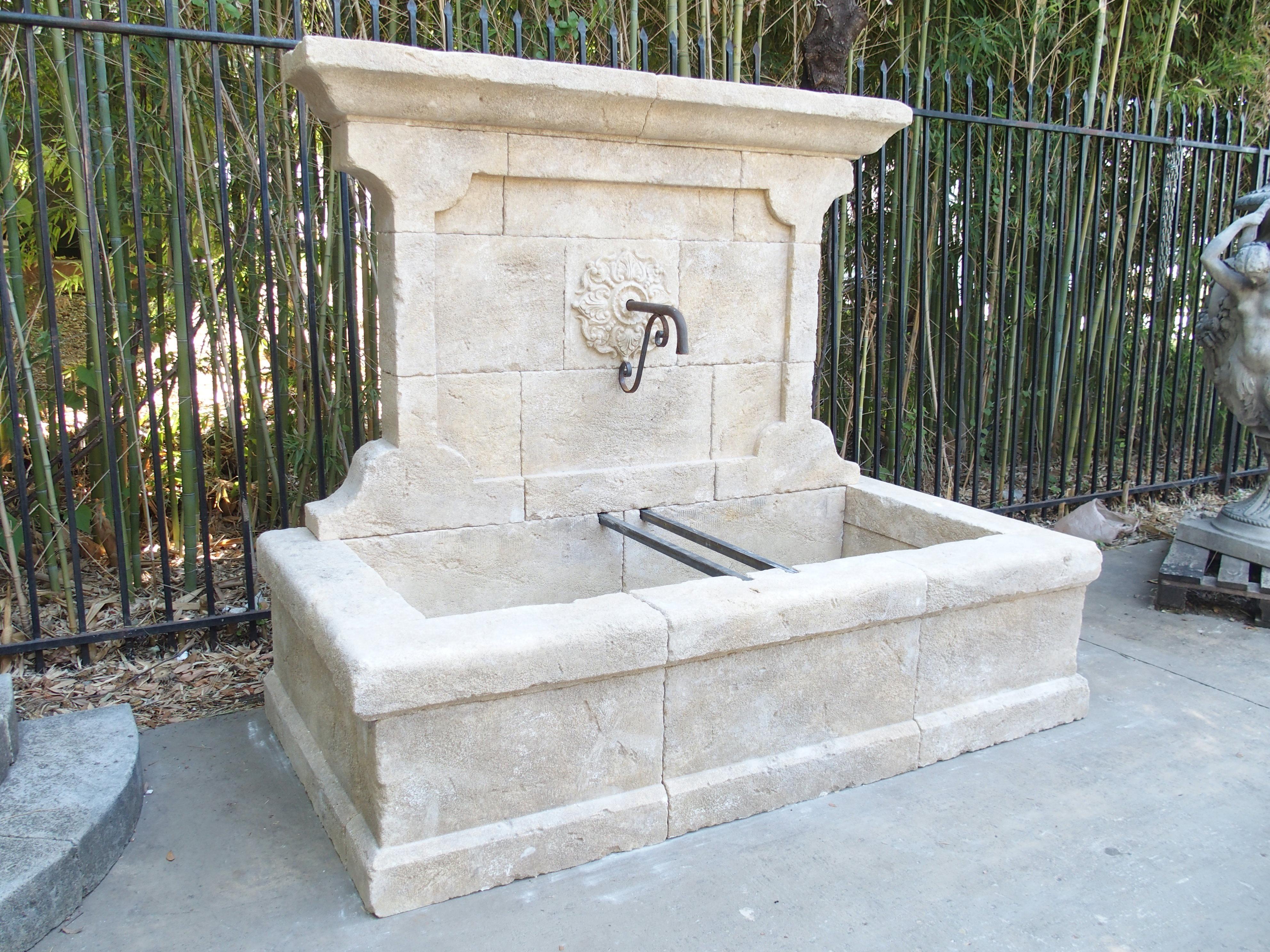 This elegant and large wall fountain from the South of France has been hand carved in local Estaillade limestone. There is a stepped out trumeau at the top and the back plate has a decorative hand carved round motif surrounding the iron S-Scroll