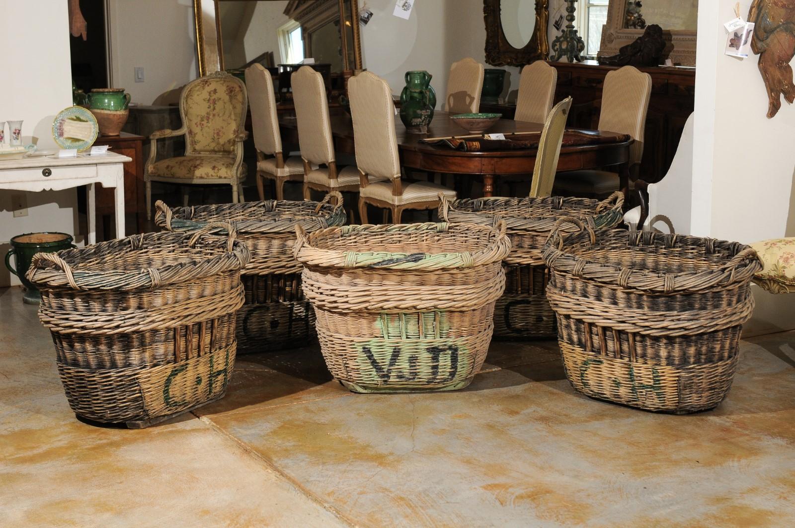 Only one left! Five large French wicker baskets from the early 20th century, priced and sold individually. Born in France in the early years of the 20th century, each of these large rustic wicker baskets features an oval shape, topped with a twisted