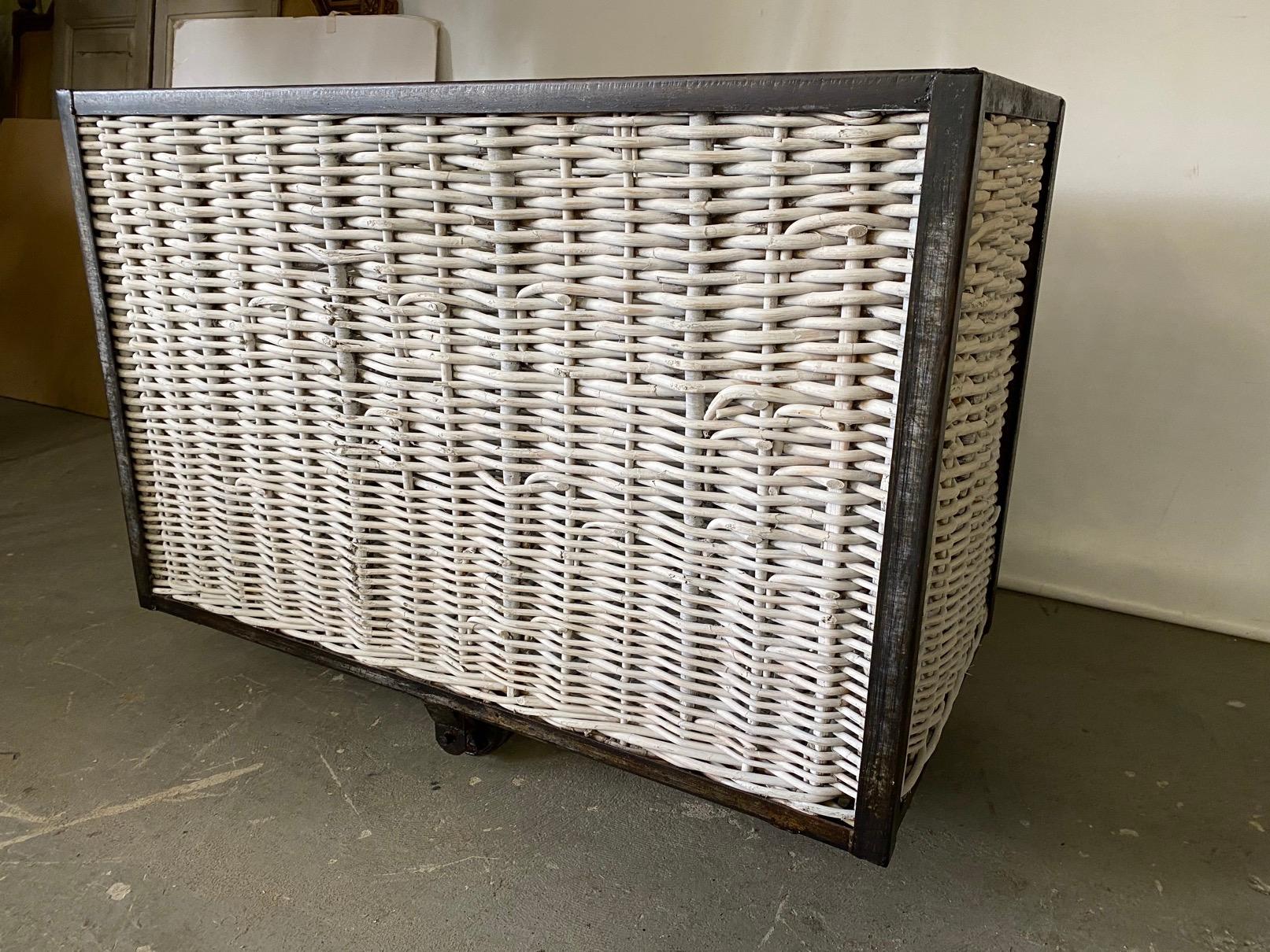 A substantial steel frame and wicker or rattan multipurpose French laundry bin on wheels. The sides and base are made from wicker/rattan. The steel frame is supported by large metal castors for easy movement. This was once used in either a