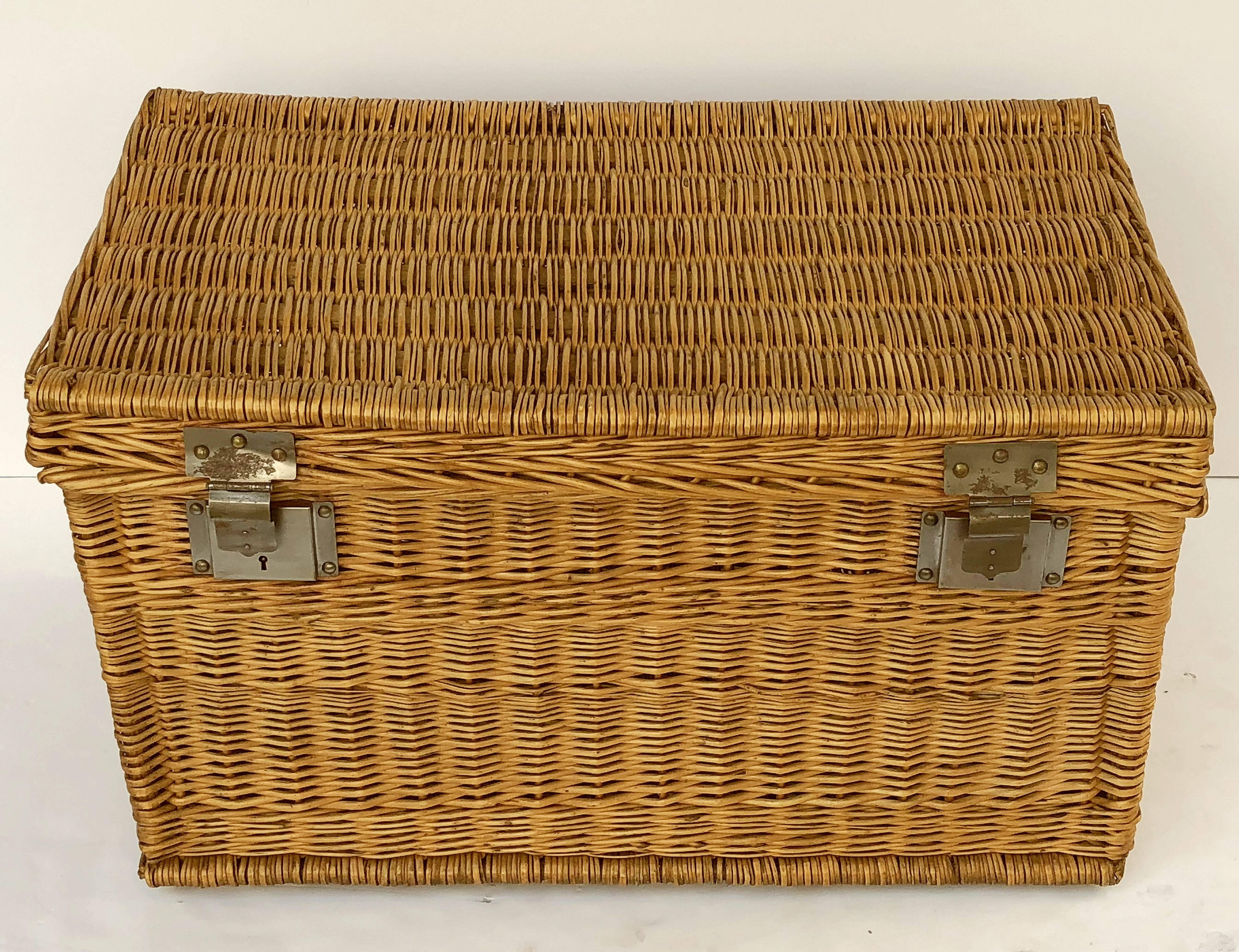 A large French basket hamper of woven willow with steel hardware and handles on each side. With wooden runners on underside.

Several available in this style, slight variations of size.

Note: Latches do not always close and lock.