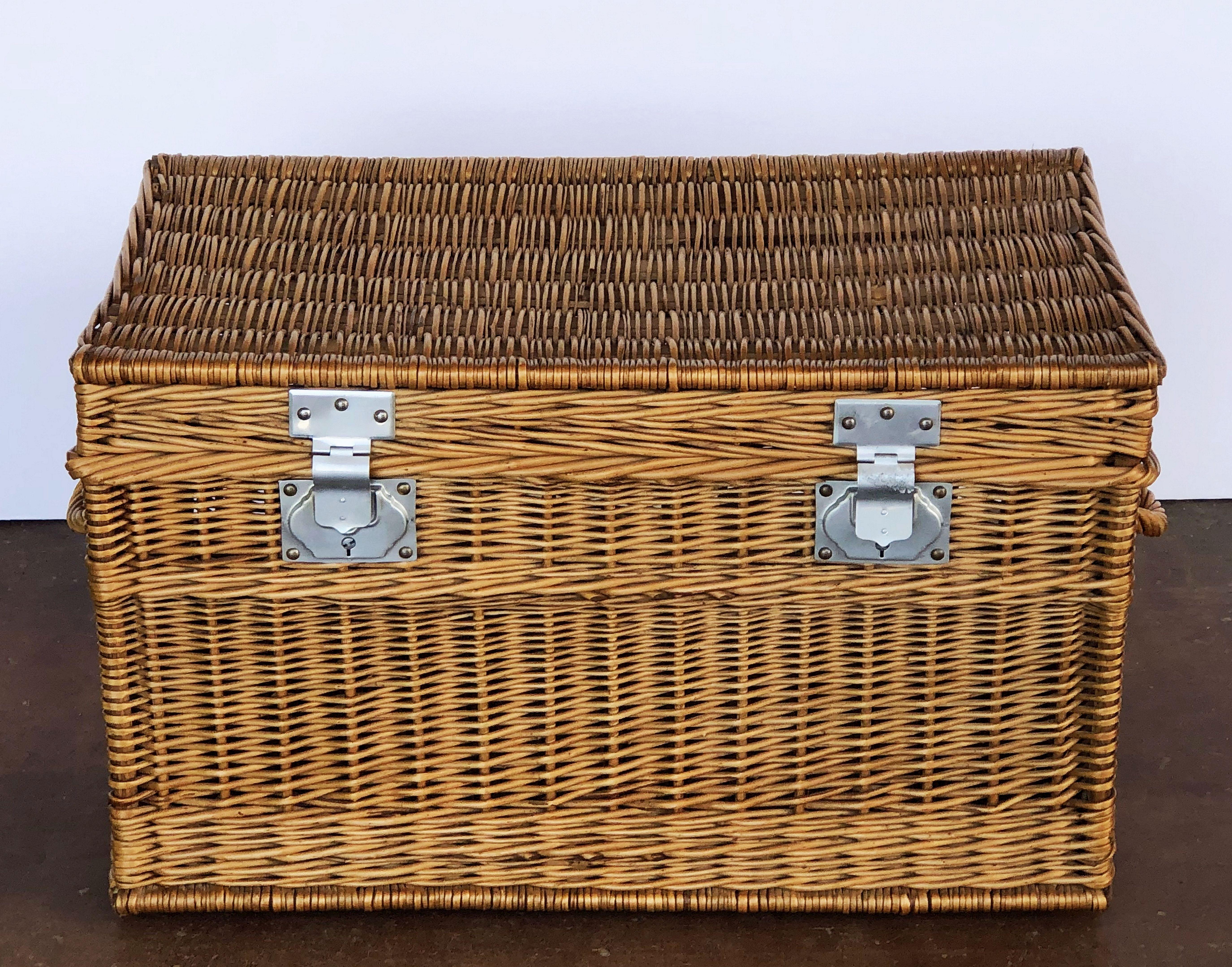 A large French basket hamper of woven willow with steel hardware and handles on each side. With wooden runners on underside.

Several available in this style, slight variations of size.

Note: Latches do not always close and lock.