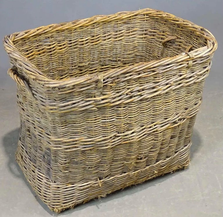 Rustic French laundry basket constructed from woven wicker reeds, features a thick braided top with handles on each end and brightly colored green painted band, reinforced and supported by a wood slat bottom. Perfect for decorating and display.