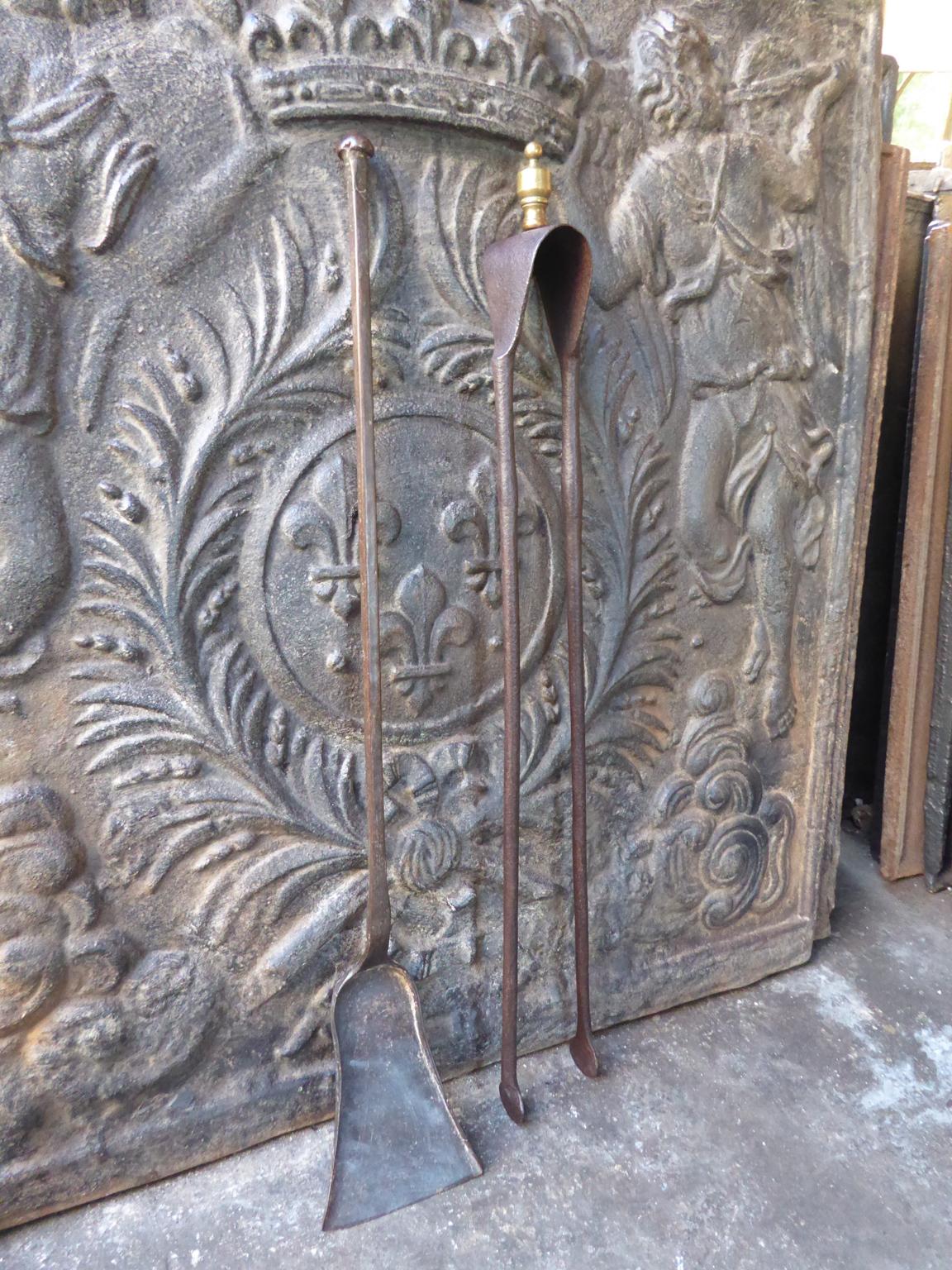 Large 18th century French Louis XV fireplace tool set consisting of fireplace tongs and a shovel. The fire irons are made of wrought iron. The tongs have a brass top. They are in a good condition and are fully functional.