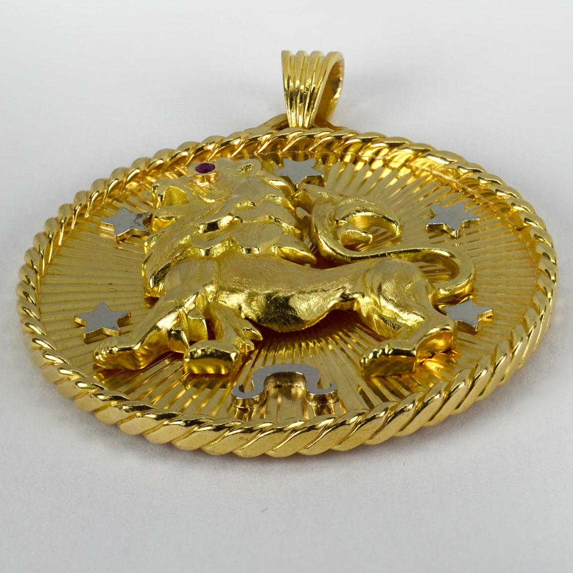 A large French 18 karat (18K) yellow and white gold pendant depicting a three-dimensional lion with a ruby eye surrounded by five white gold stars and the Zodiac symbol for Leo. The reverse with a sunburst pattern, centering on the initial M. 
