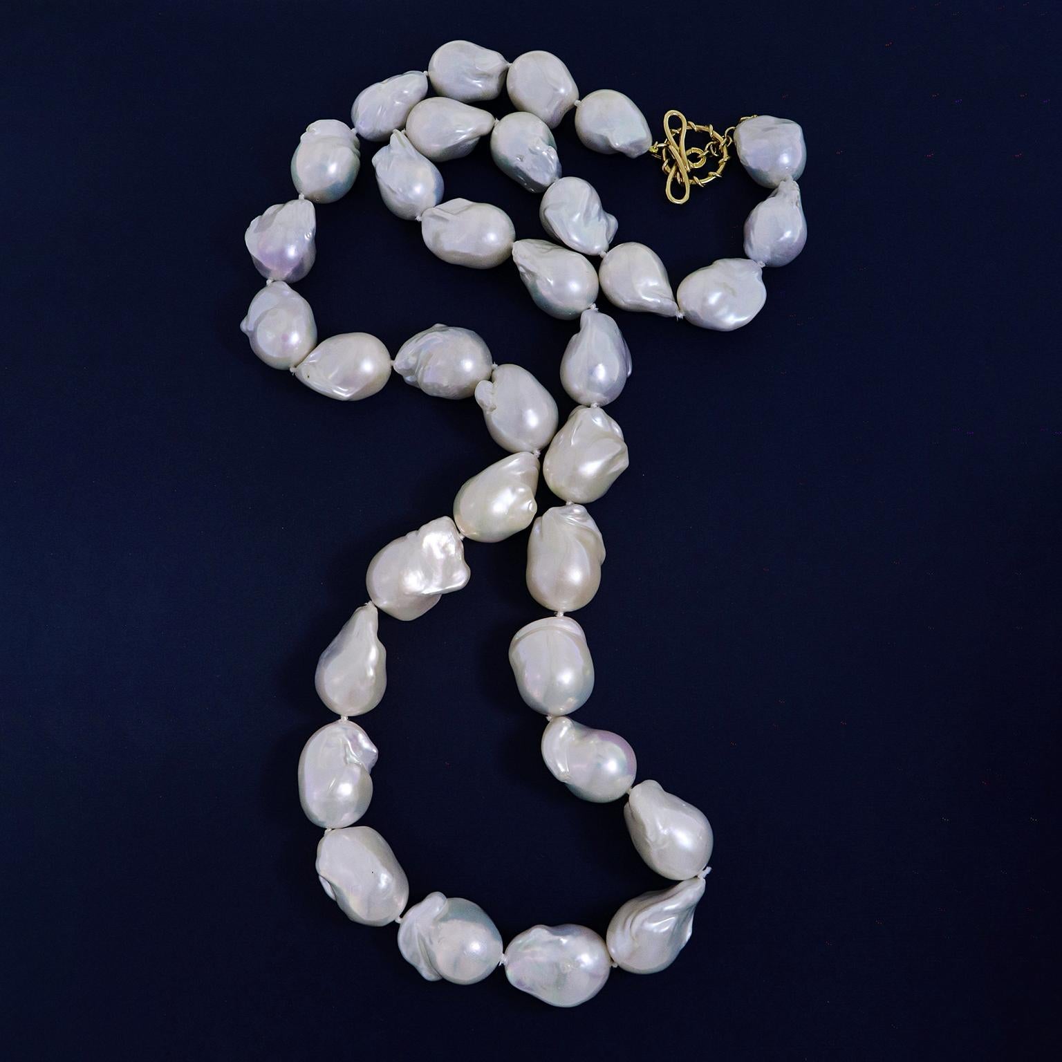 An atmosphere of the sea is evoked by this pearl necklace. Large freshwater baroque pearls are collected together on a wire, each reflecting an iridescent radiance off their unique nacre bodies. The total weight of the gem is 900 carats. An 18k