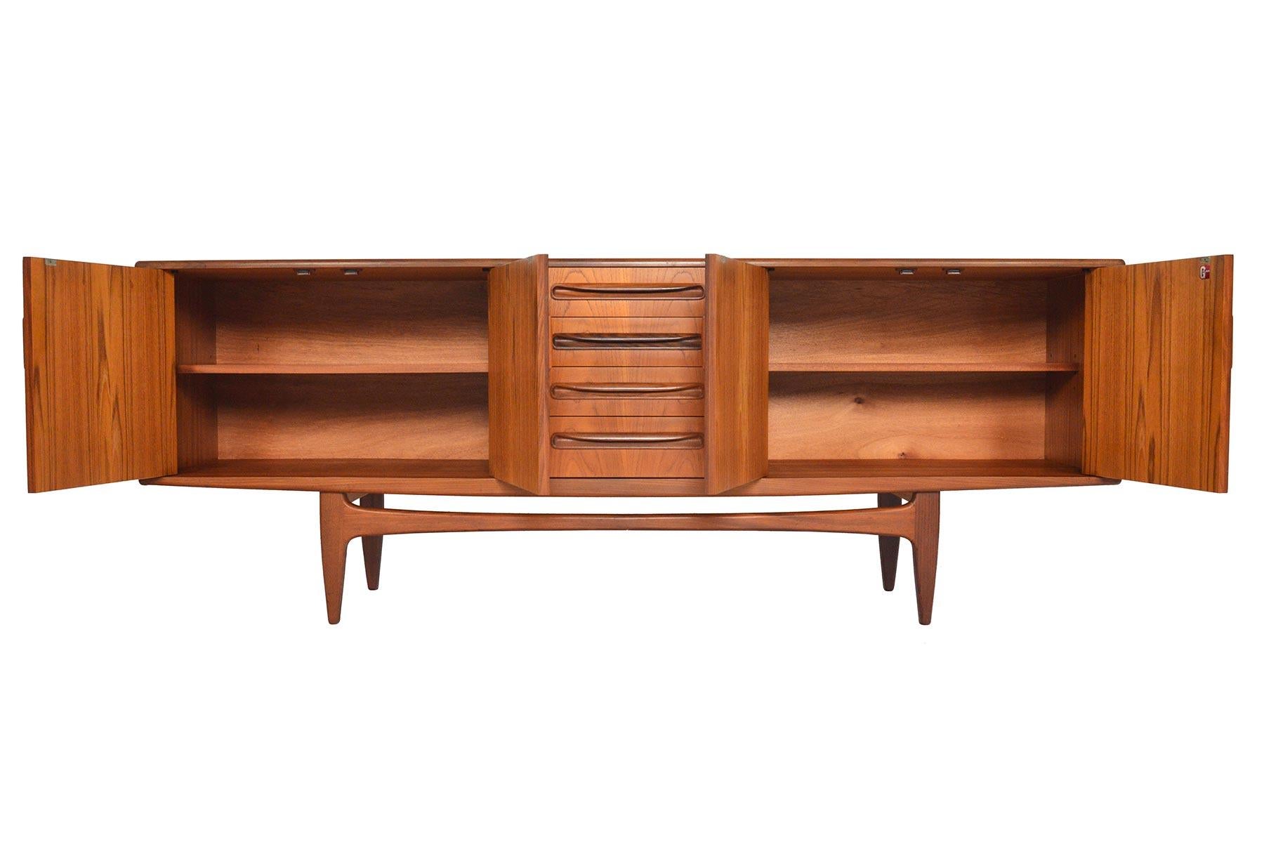 This large Mid-Century Modern G Plan Fresco teak credenza was designed by Victor Wilkins in the 1960s. Beautiful afromosia pulls adorn the drawers and doors of this piece. Left and right doors open to reveal adjustable shelving. Case floats upon a