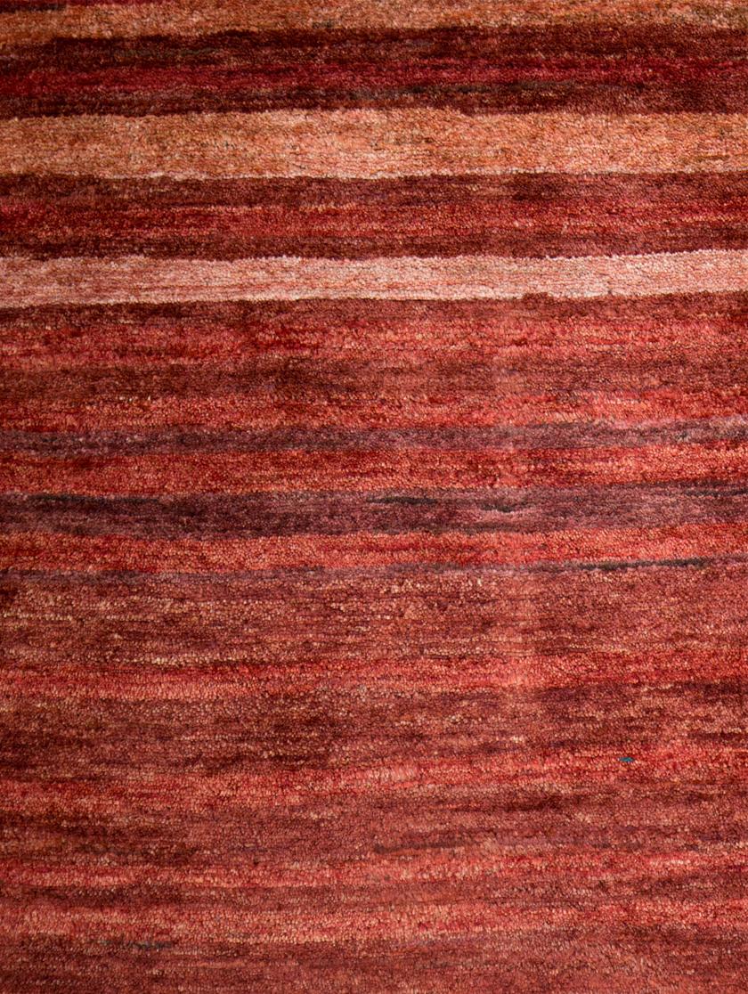 Large Deep Red Contemporary Gabbeh Persian Wool Rug. The undulating lines in reddish hues remind us first, of the high desert Zagros mountains where the Qashqai roam and live. It might remind others of a cross-section of petrified wood. No matter