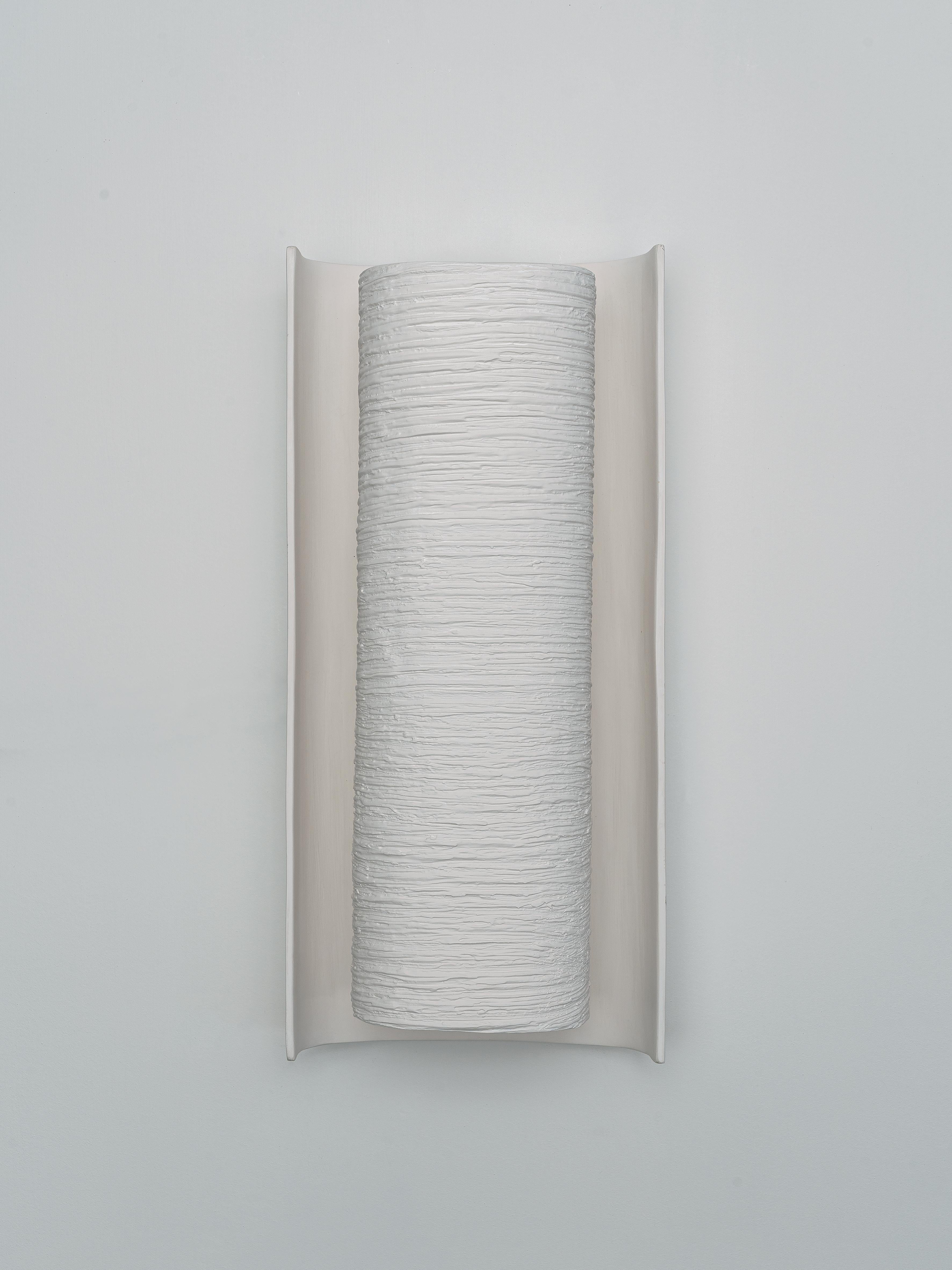 Die Wandleuchte Galba ist eine beeindruckende Mischung aus Kunst und Funktion. Diese handgefertigte Leuchte, die aus zwei geformten Teilen auf einer Metallarmatur besteht, wirft ein sanftes, angenehmes Licht in den Raum. Die Textur der Vorderseite