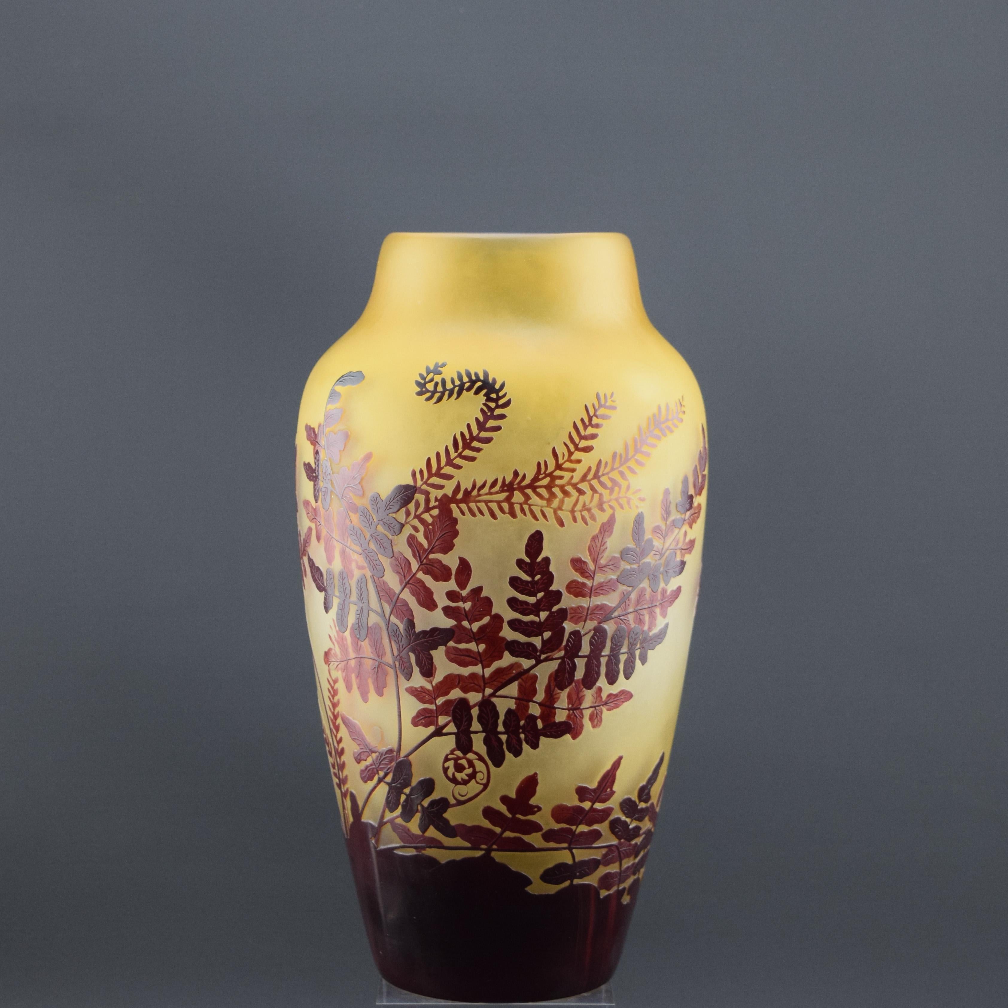 Gran jarrón de helecho de vidrio camafeo Galle c1920. Jarrón profusamente decorado con frondas de helecho en rojo oscuro y más claro sobre fondo limón. Firmado en el camafeo con una elaborada firma de Galle.

El estado es muy bueno, hay una burbuja