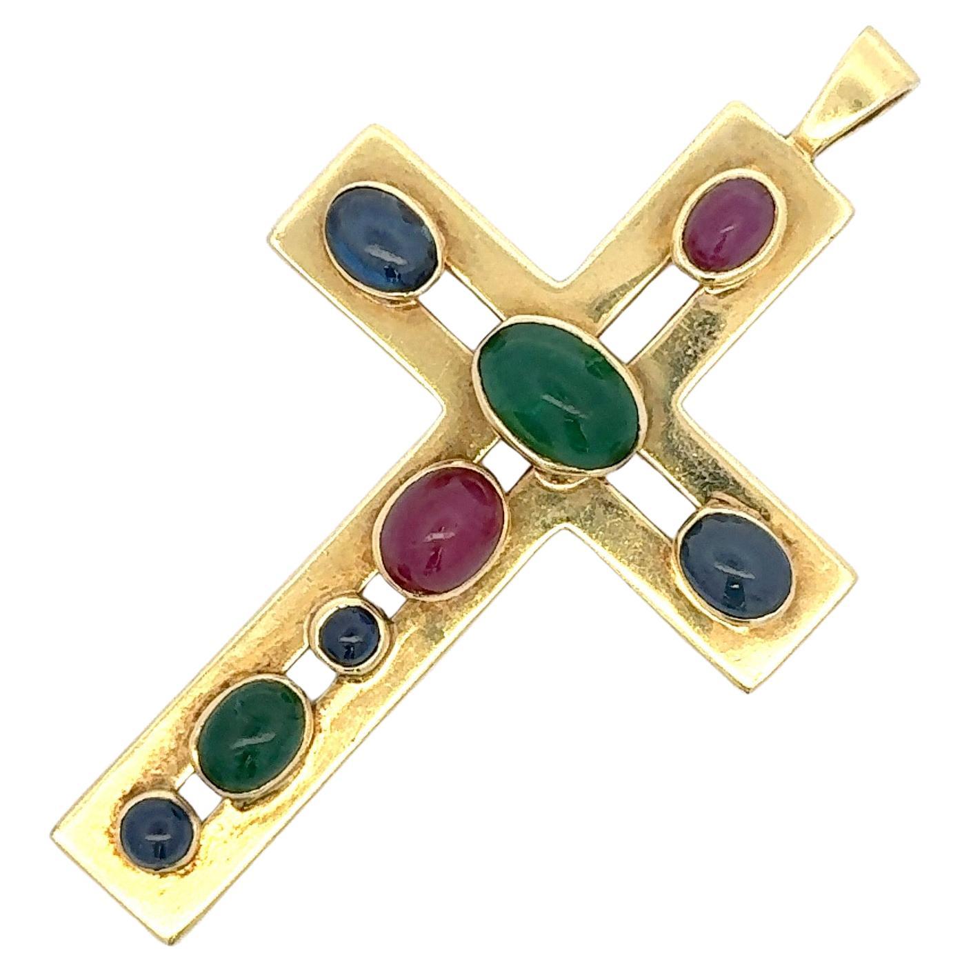 Une grande croix en or jaune 18 carats, 28,5 grammes, ornée d'émeraudes, de rubis et de saphirs en cabochon. 
Chaîne non incluse.
