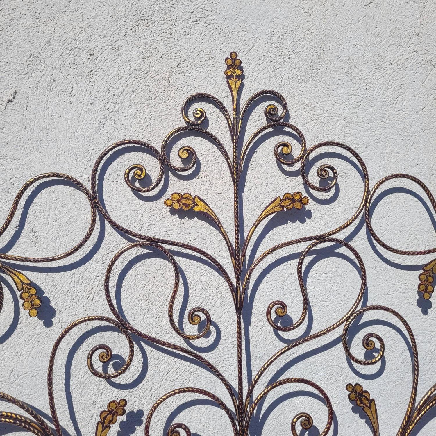 Gran cama de hierro pintada en burdeos, con una decoración de flores y follaje realzada con oro, 4 clavijas rematan cada montante  

Buen estado general, desgaste por el uso, barras laterales quizás cambiadas; 1 tornillo cambiado  

Obra genovesa