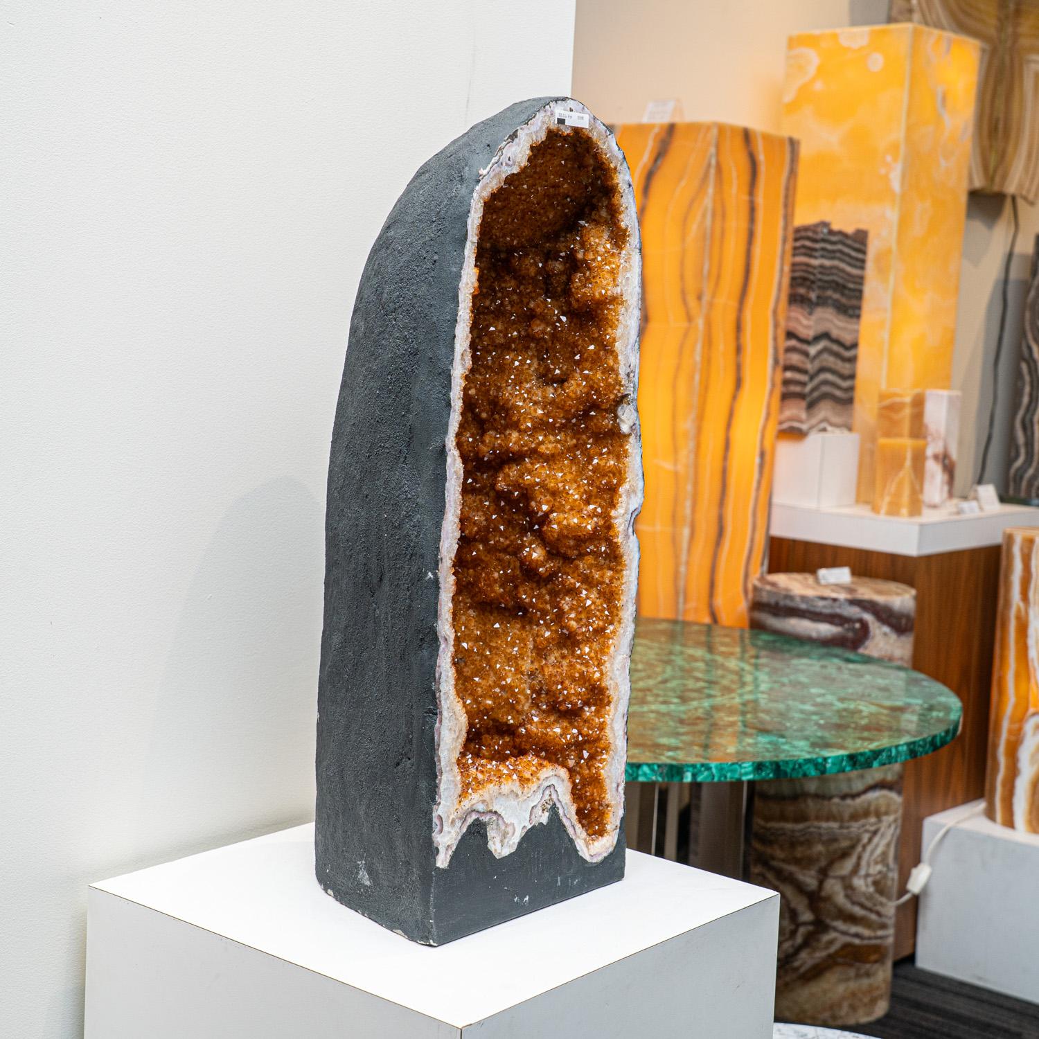 This Massive museum quality, Citrine crystal clustered geode from Brazil is a top quality natural formation of gem citrine. This specimen showcases a full lining of radiant, golden quartz crystals and features vibrant orange and yellow hues with