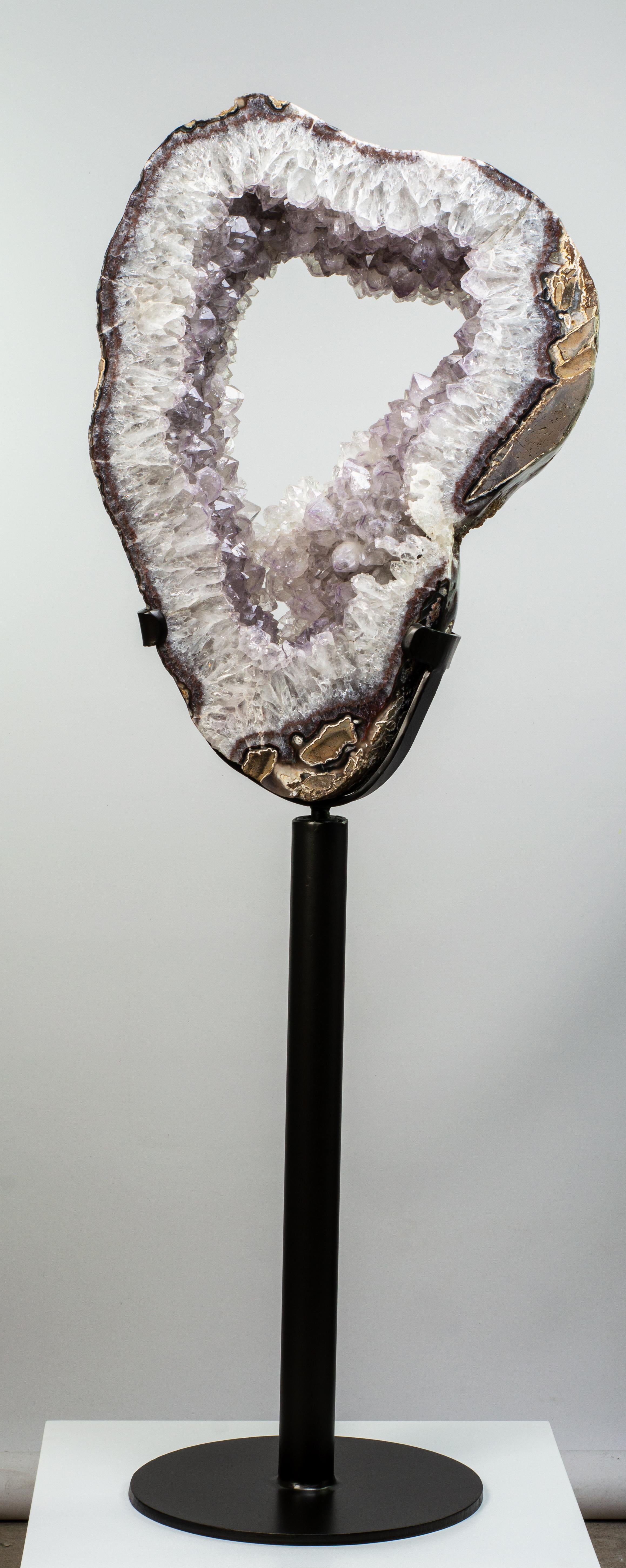 Expertly cut from a large geode, this slice preserves large lilac crystals of amethystine quartz, bordered by a thin agate layer and a rough basalt exterior.

This piece was legally and ethically sourced directly in the prestigious mines of