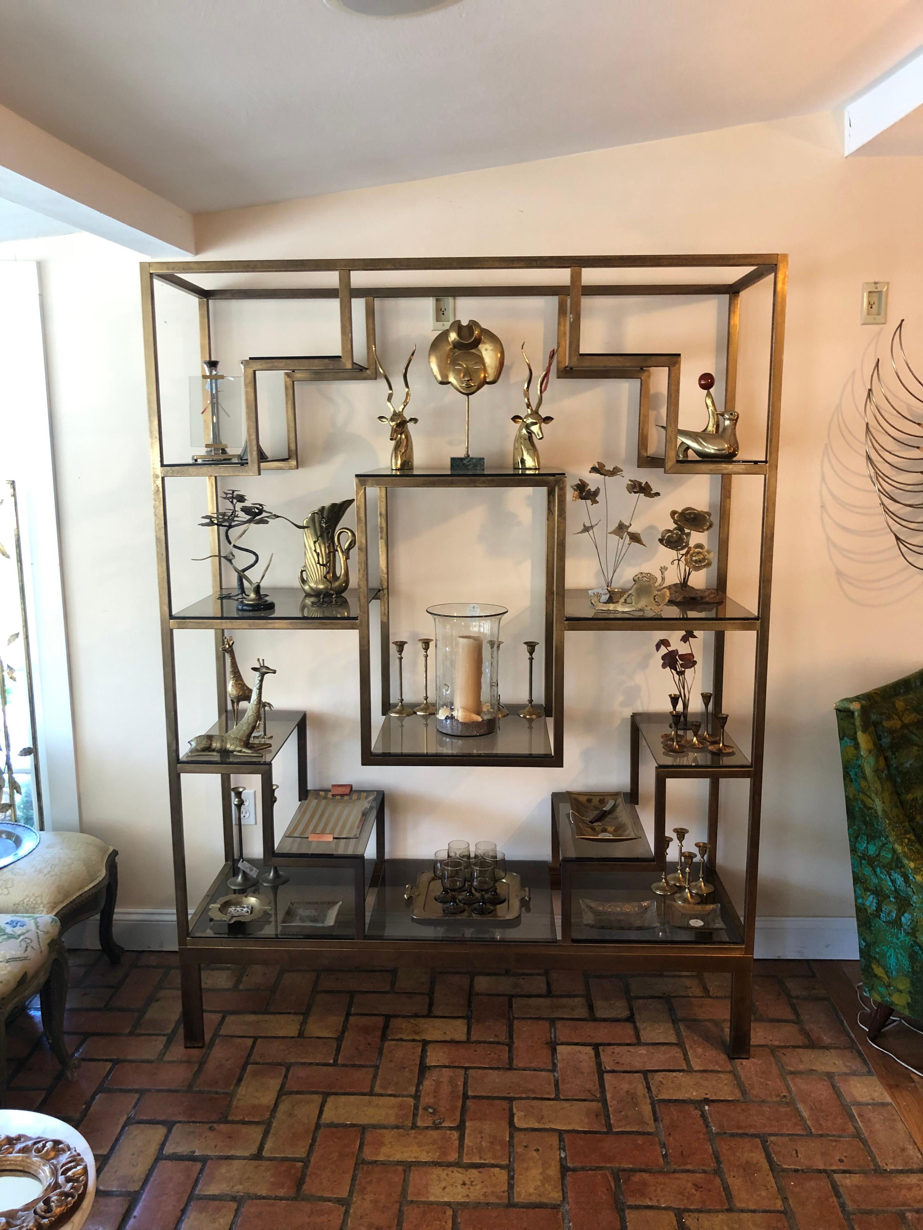 Large geometric brass étagère attributed to Romeo Rega. Made in Italy. Amazing quality and design. Antiqued brass finish with smoked glass shelves. High end designer piece that will light up any room. Great for display.