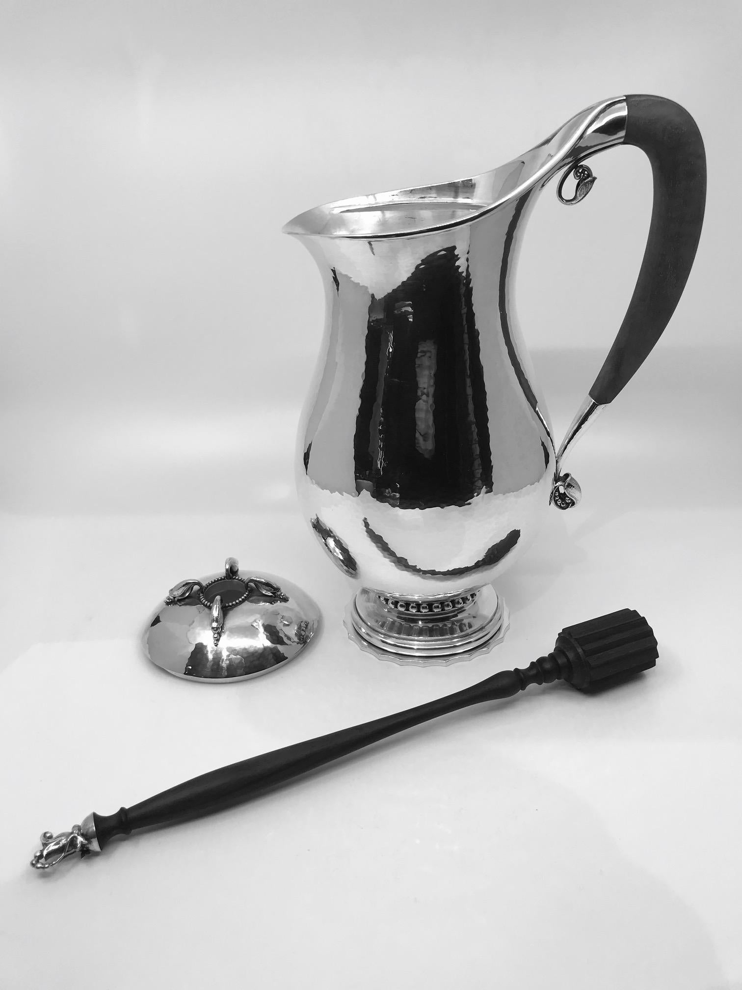 Perfect for the winter season a Georg Jensen sterling silver chocolate pot #460B, designed by Georg Jensen in 1925. With a mahogany handle and a silver mounted rosewood stirrer, 13? (33cm) high, weight is 43.65oz (1,358g). This pitcher comes in the