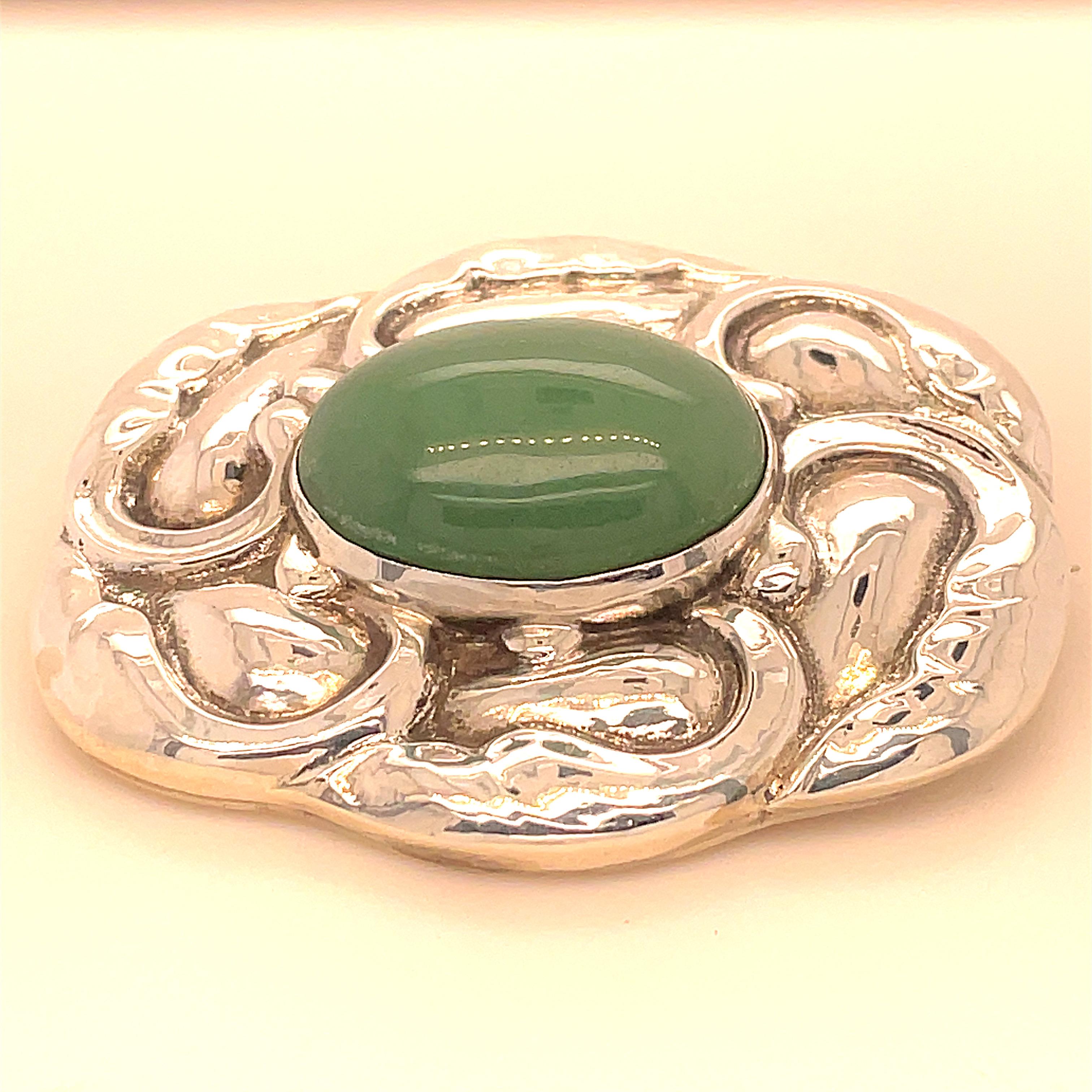 Large sterling silver pin.  Made and signed by GEORG JENSEN.  Rectangular with rounded corners.  With an applied puffy leafy border pattern.  In the center is a large cabochon chrysoprase.  2