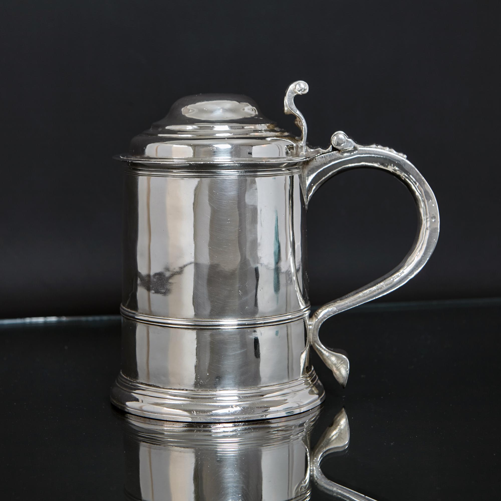 Feiner und originaler frühgeorgianischer Silberkrug mit klassischem, gestuftem Sockel, abgestuftem, gewölbtem Deckel und einfachem, um den Korpus herumgelegtem Gürtel.  Der scharniergelagerte silberne Deckel ist mit einem gegossenen silbernen