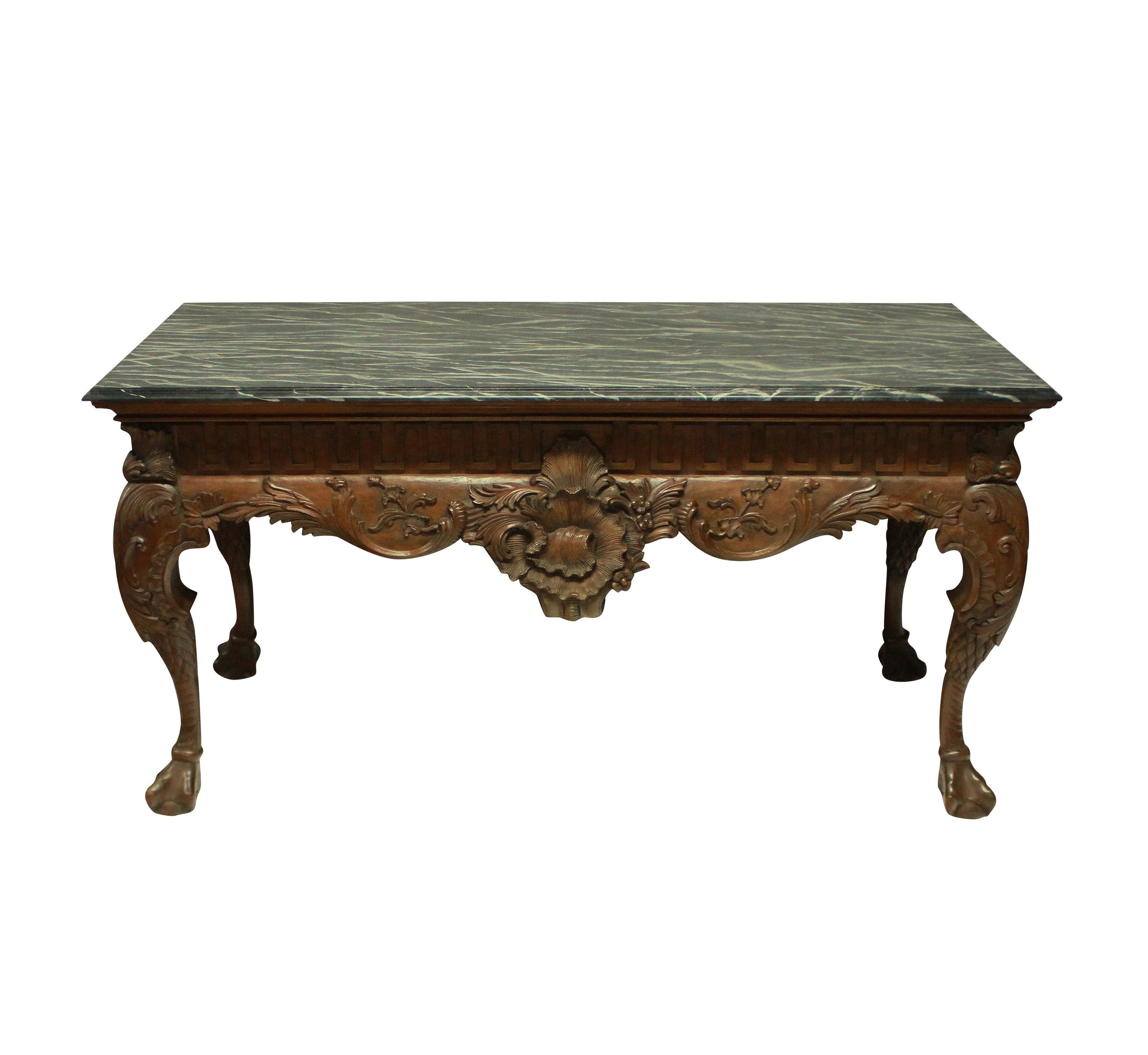 A large and beautifully carved George II style mahogany centre table, with Greek key frieze and a faux marble top. It is carved on all four sides, so could be used as a console or centre table. The table has a good patina throughout.
 