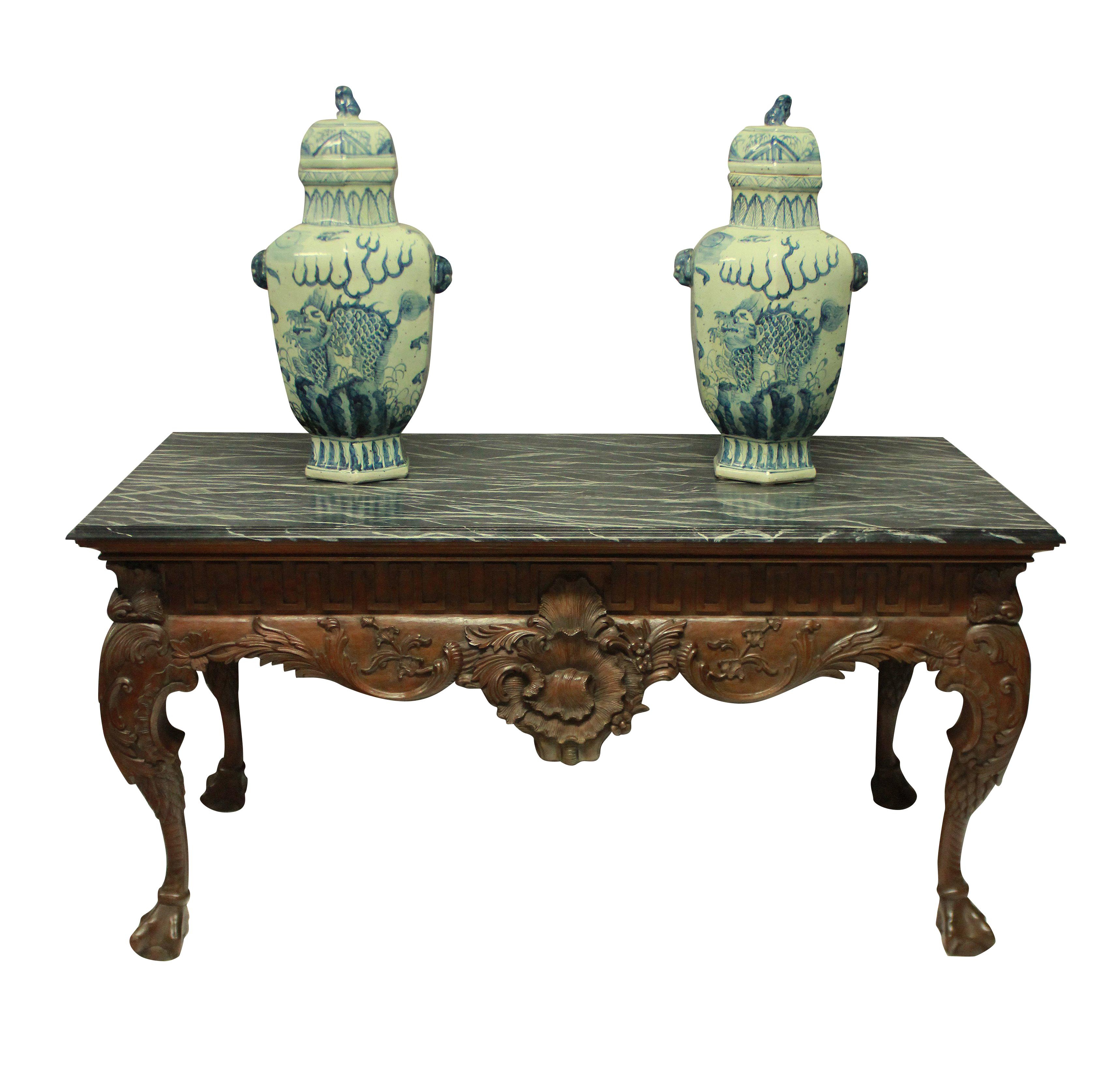 A large and beautifully carved George II style mahogany centre table, with Greek key frieze and a faux marble top. It is carved on all four sides, so could be used as a console or centre table.

 