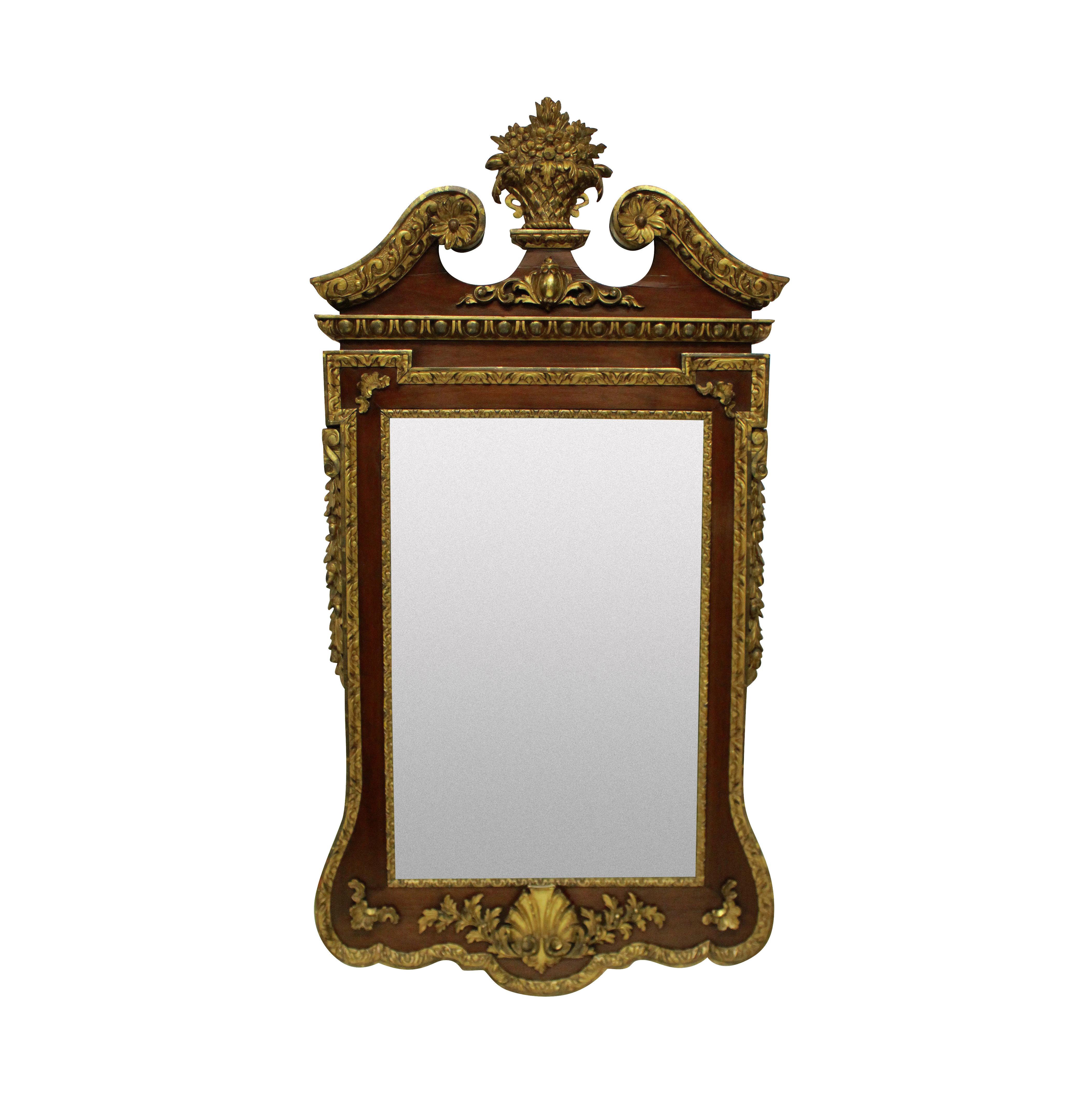 A large and finely carved walnut and parcel-gilt George II style mirror with a beveled plate.