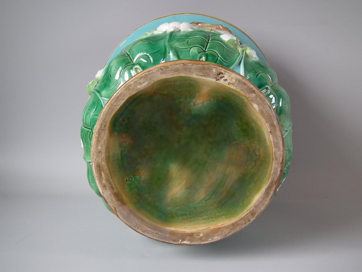 George Jones Majolica jardinière which features water lilies, birds (Reed Buntings), bulrushes and dragonflies. Turquoise ground version. Coloration: Turquoise, green, brown, are predominant. The piece bears maker's marks for the George Jones
