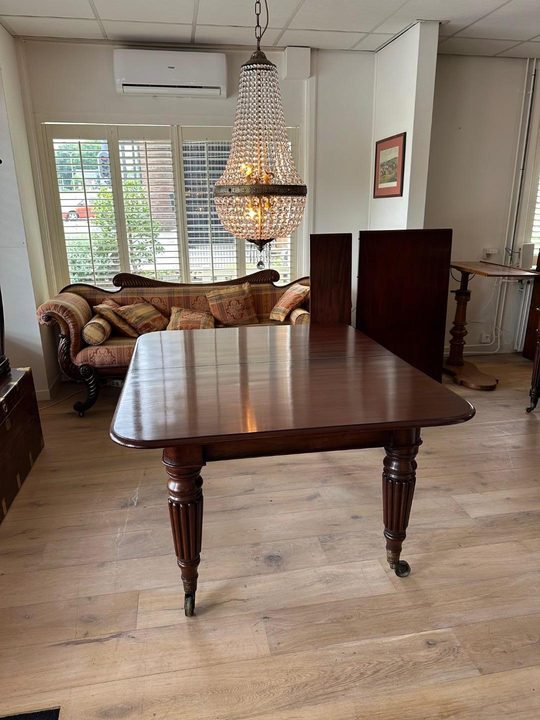 Beautiful antique mahogany Georgian dining table with two additional original leaves to make it larger. (The table once had a total of three additional leaves.) The table can be slid apart, after which one or two leaves can be inserted. The leaves