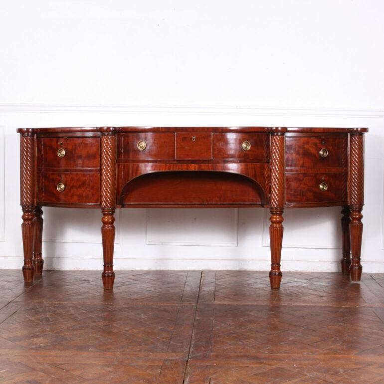 Large rare Irish flame mahogany sideboard with a dramatic bowed profile. Two central drawers flanked with a pair of curved-front ‘faux drawer’ cabinets. Spiral-turned details and standing on turned tapering reeded legs. C. 1790, in excellent