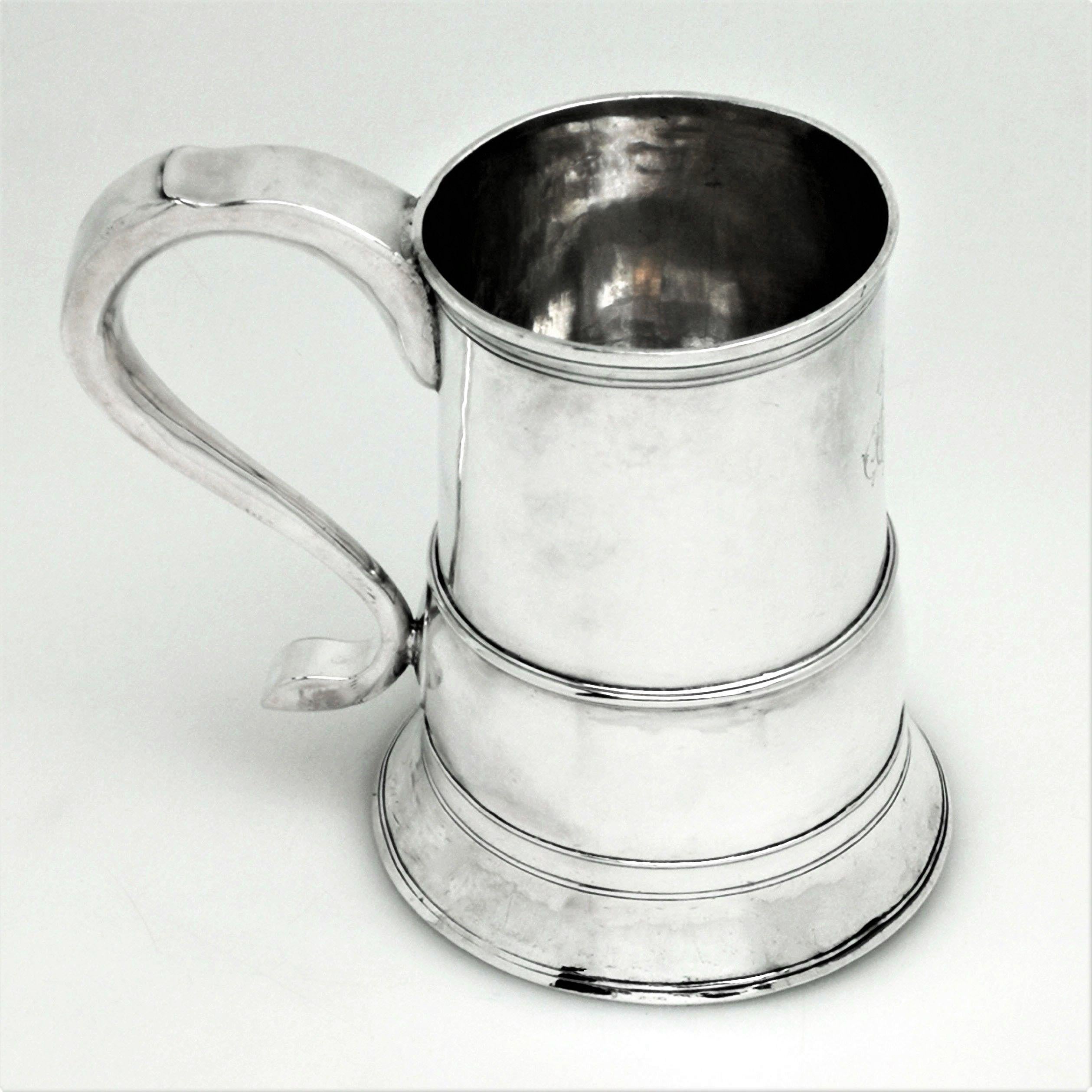 An impressive antique George III solid silver beer mug / tankard. This tankard has an unusual bellied band around the base of the body, deviating from the traditional straight sided design. This bellied band allows for an increased capacity while