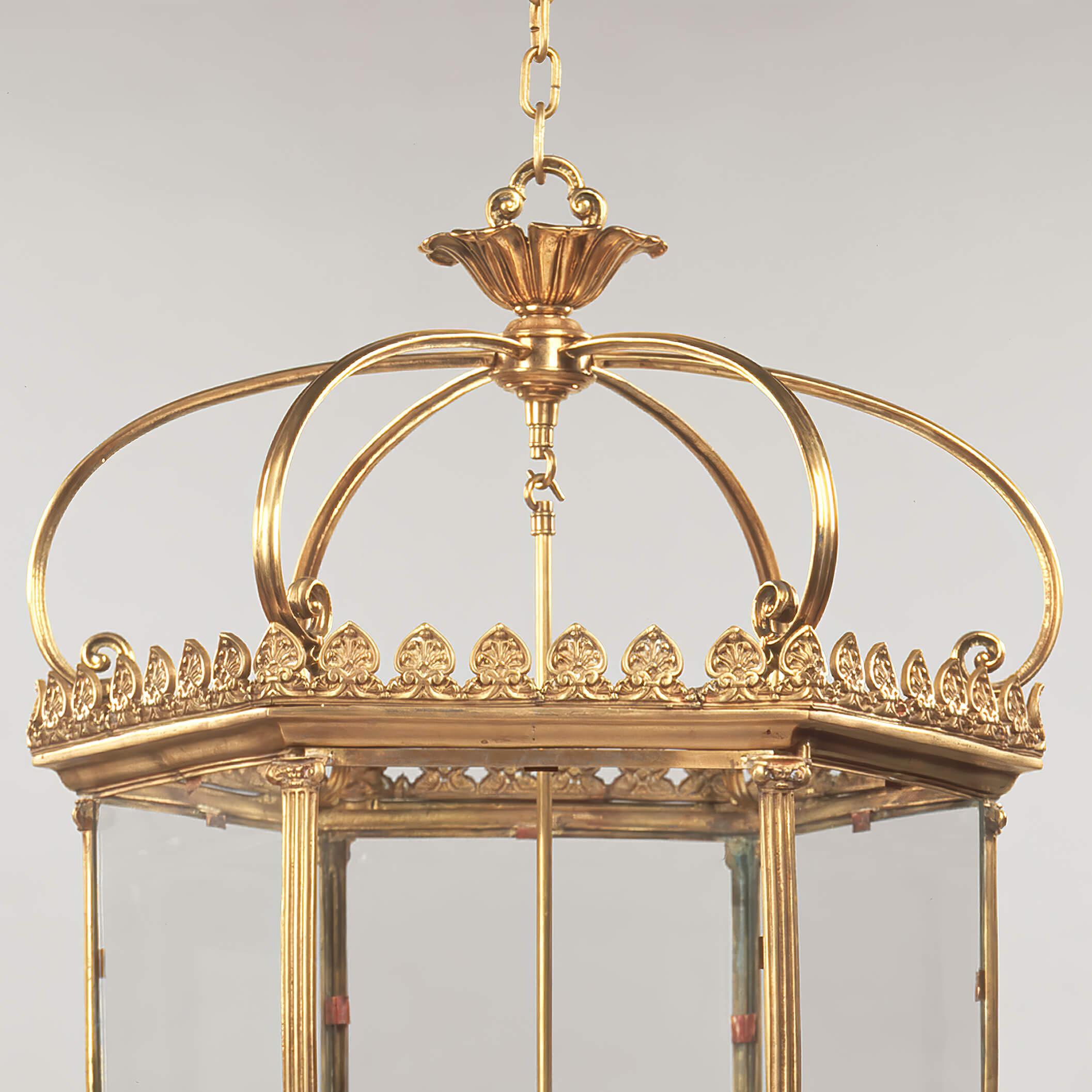 A Grand Georgian style hexagonal six-light hall lantern with a regal crown above a fleur-de-lis decorated gallery with six glass panels, an opening door, framed by Roman Ionic columns with drop finials.

Dimensions: 25