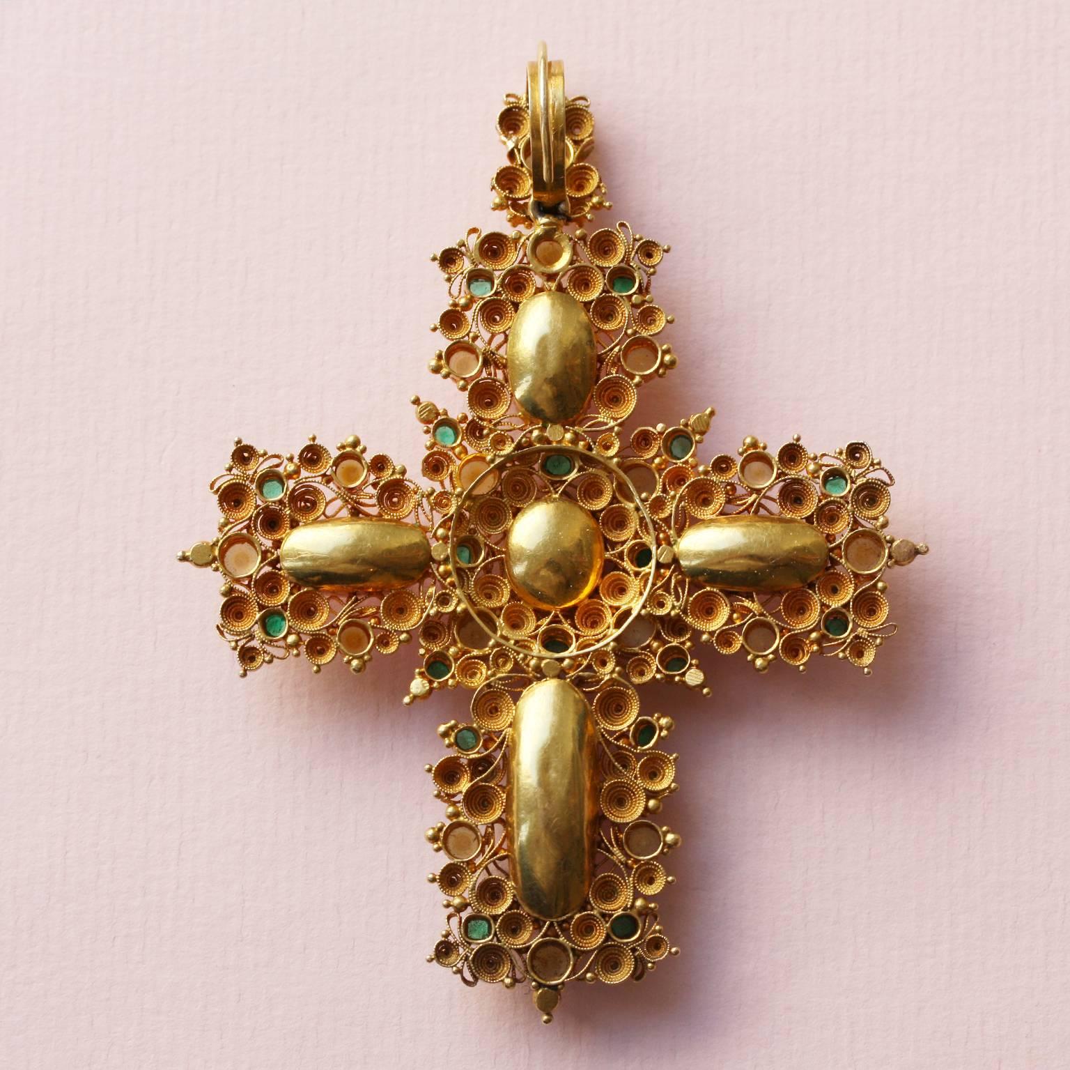 A large 18-carat gold cross set with natural pearls, natural emeralds all in open setting, and five large pink topazes in closed setting. The  highly ornate gold decorations in the cannetille technique, were fashionable in England from 1790-1830.