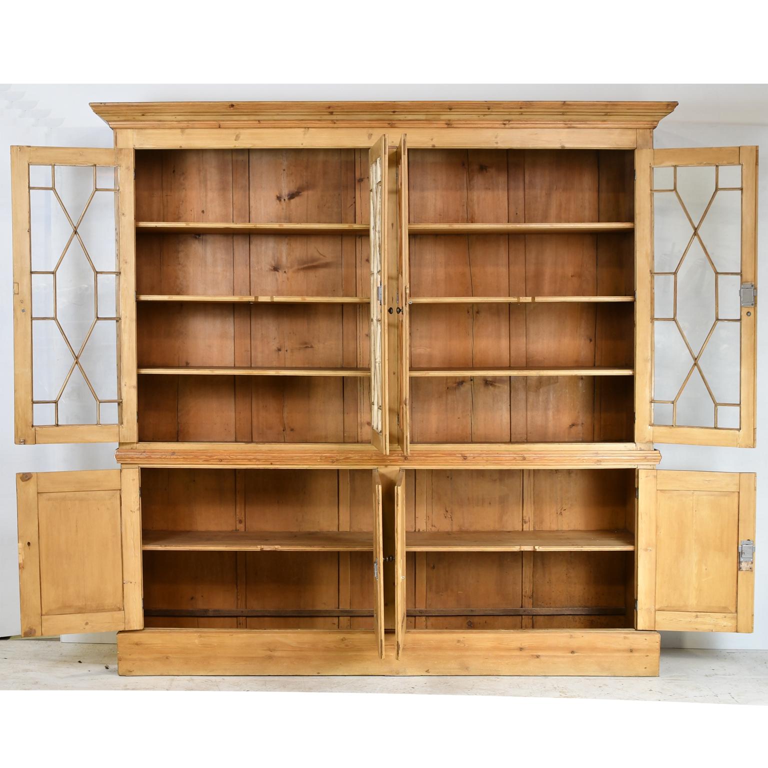 English pine bookcase/display cabinet with glazed doors in upper cupboard with fixed shelves and lower cupboard for storage resting on a plinth base.  19th century and later. 
Breaks down into 2 sections for transportation and installation
Measures: