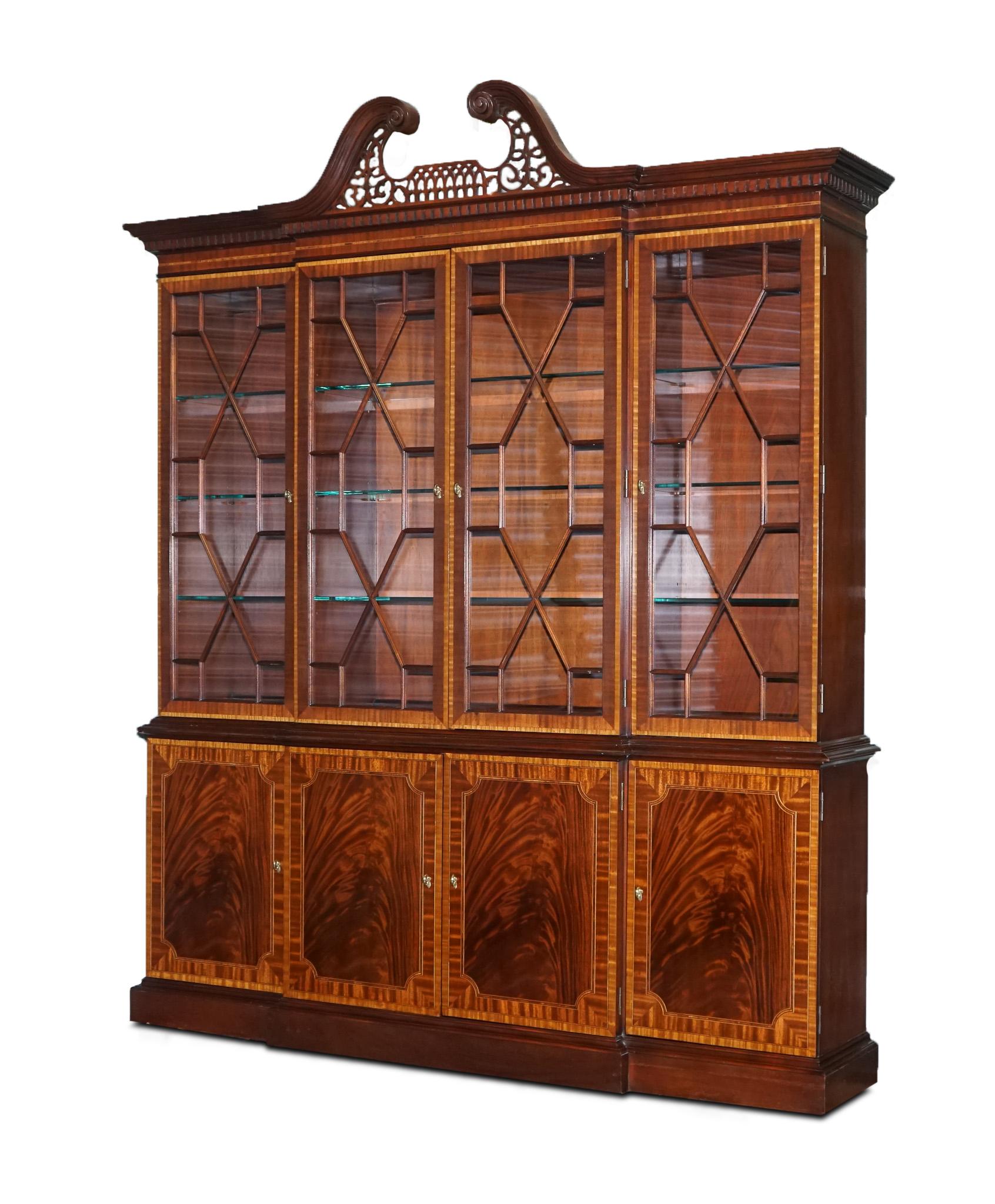 We are excited to offer for sale this large Georgian-style mahogany breakfront bookcase Councill furniture. 

It has four glass doors with wood mullions framed with ribbon stripe mahogany and satinwood banding.

All glass shelves are adjustable