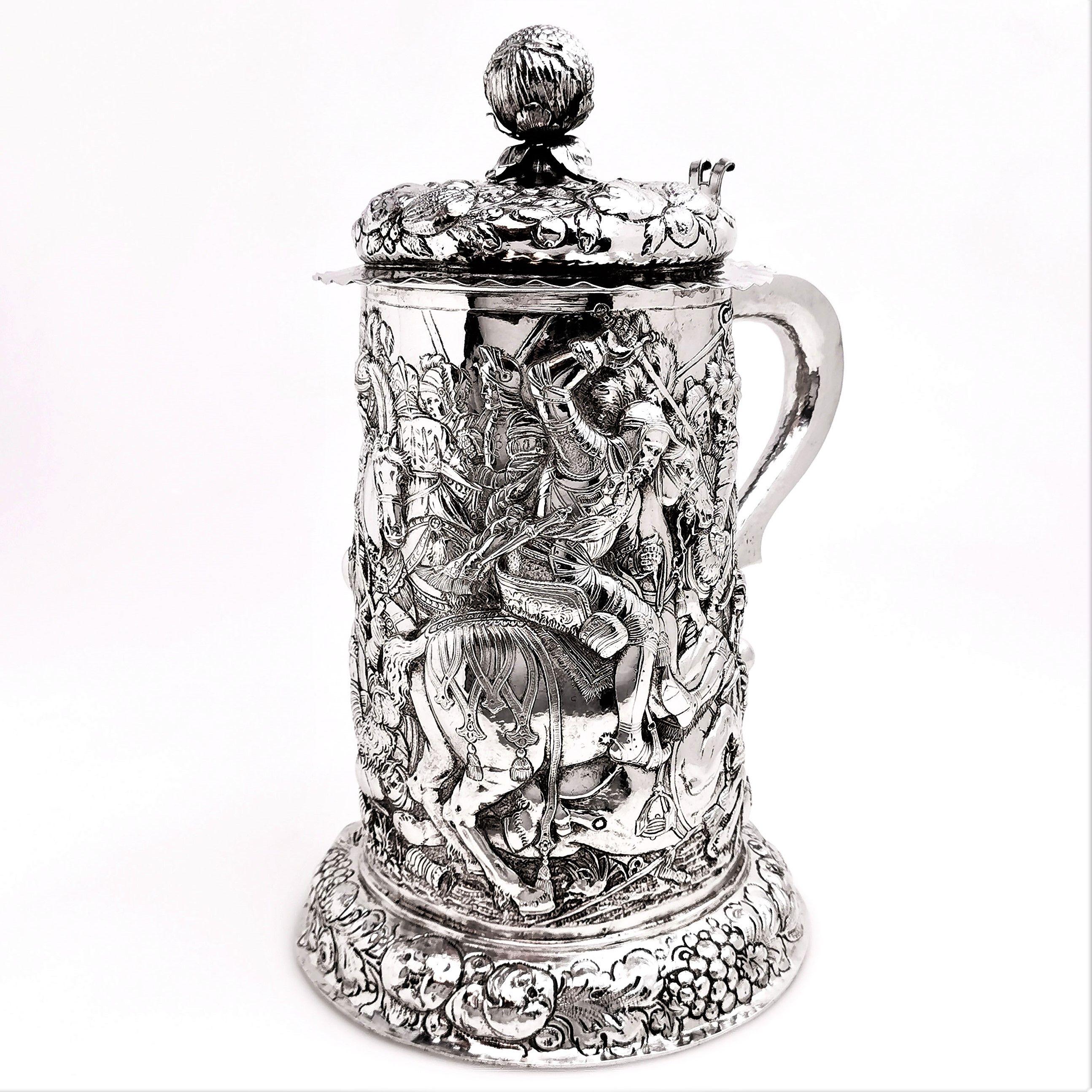 A magnificent over sized antique German solid silver Historismus Tankard / Stein covered in an ornate design featuring a group of Knights in Armour in the midst of a battle.The base of the tankard has a wide spread pedestal foot, also featuring