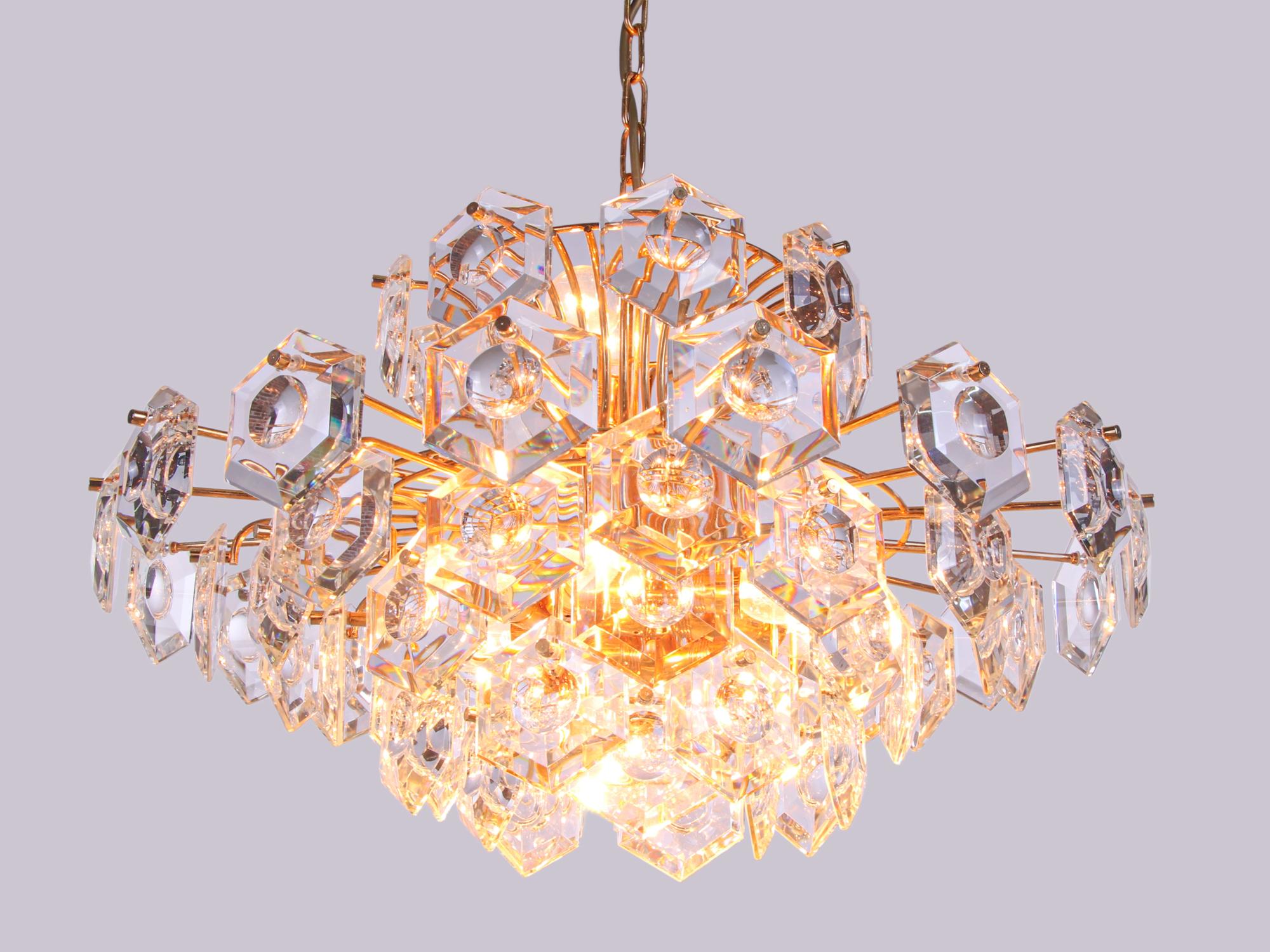 Elegant large five-tier chandelier with sculptural faceted lens crystals on a gold-plated brass frame. Chandelier illuminates beautifully and offers a lot of light. Gem from the time. With this light you make a clear statement in your interior