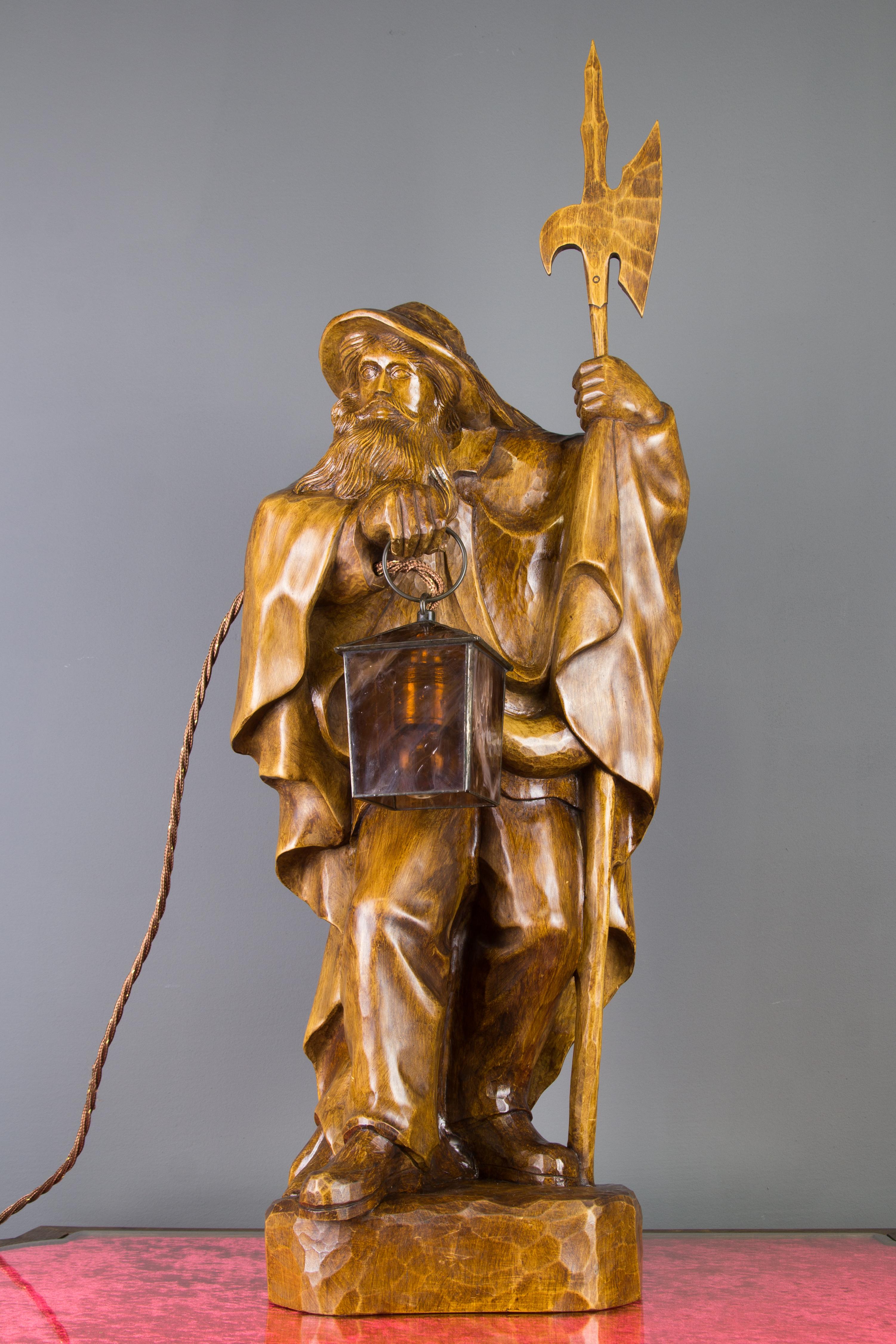 A masterfully hand-carved wooden lamp features a large sculpture of a night watchman with a lantern and halberd. Lantern is made of glass and iron. This beautiful sculpture lamp can be used as a floor or a table lamp. Signed WB. Germany, mid-20th