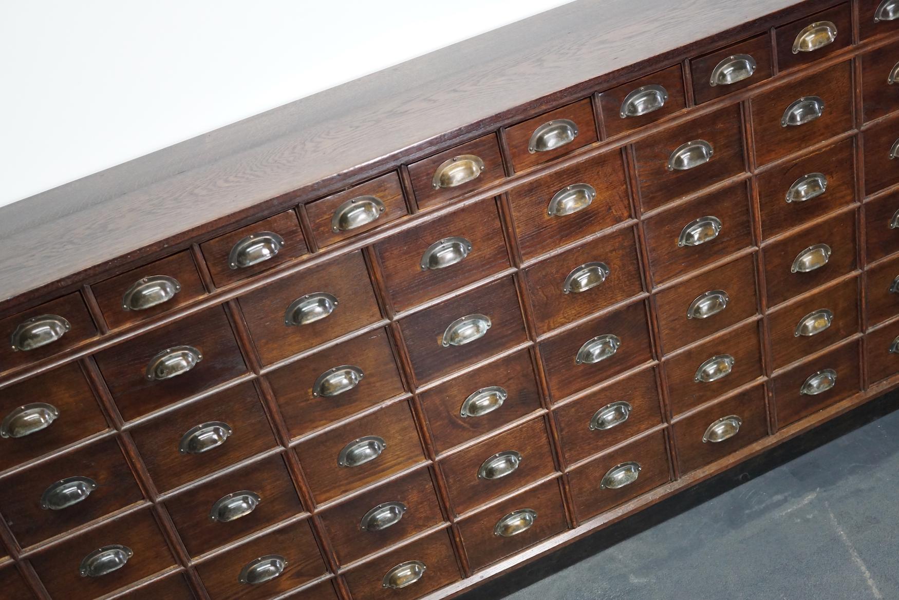 This solid oak apothecary cabinet was made circa 1920s in Germany. It features drawers in two sizes with brass cup handles. The interior dimensions of the drawers are: D W H 29 x 18 x 12 cm and 29 x 12.5 x 6.5 cm.