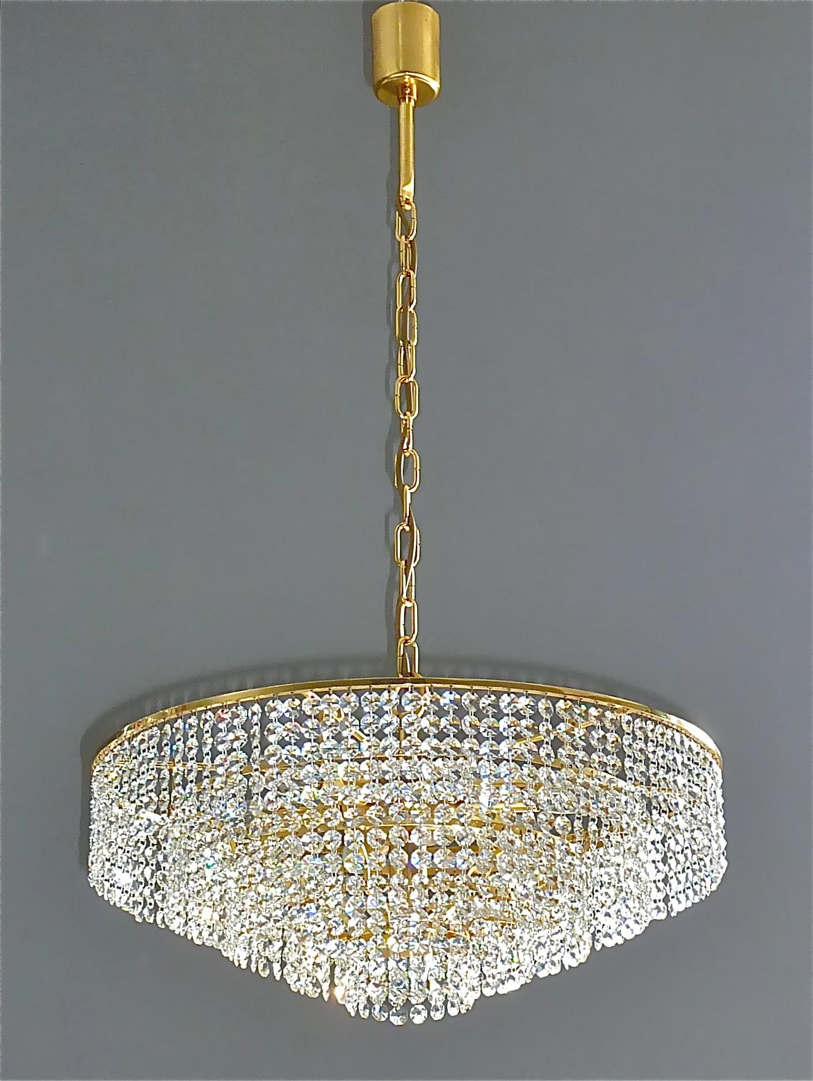 Classic large and precious gilt brass and crystal glass chandelier made by high class lighting company Palwa, Germany, circa 1960. The chain-hanging chandelier has 5 cascading tiers with lots of high lead hand-cut faceted crystal glass strings which