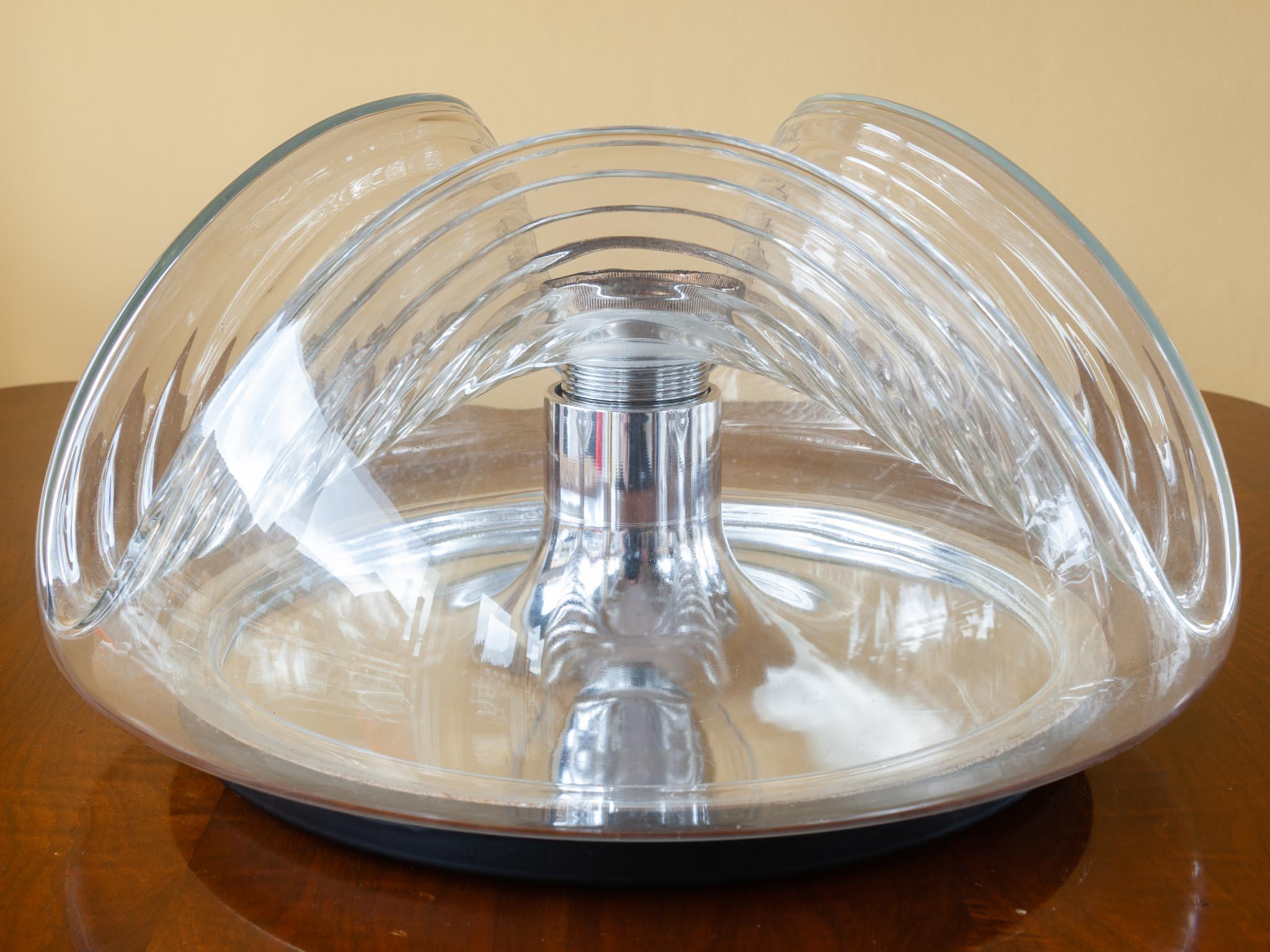 1970s 'Wave' clear glass wall or ceiling light with a chrome reflective base plate designed by Kock and Lowy for Peill & Putzler Germany. A Space Age futuristic light which is a design Classic having won a number of awards. The light socket shows