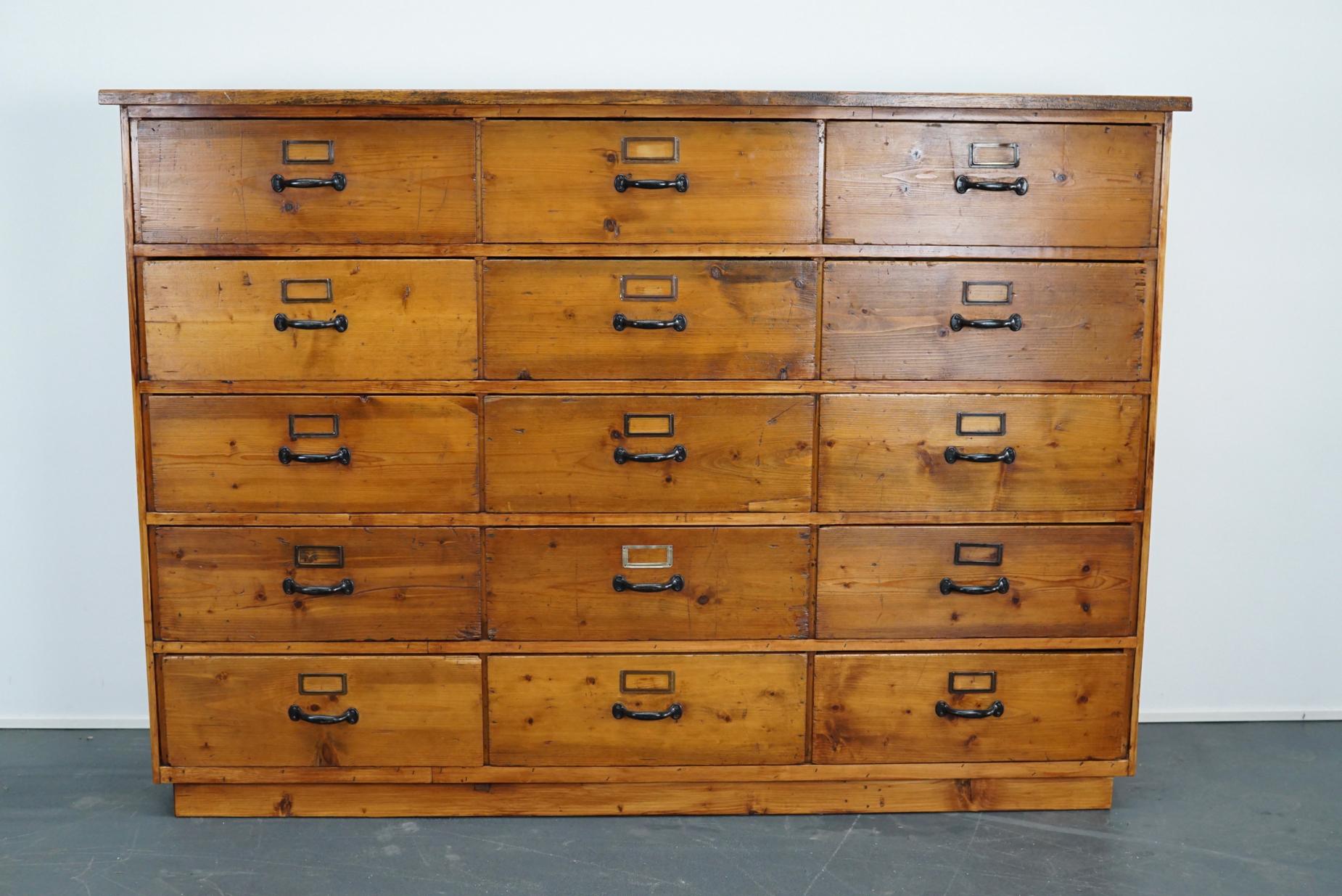 This apothecary cabinet of drawers was designed, circa 1950s in Germany. The piece is made from pine and features 15 large drawers with metal hardware. The interior dimensions of the drawers are: D 38 x W 49 x H 18 cm.