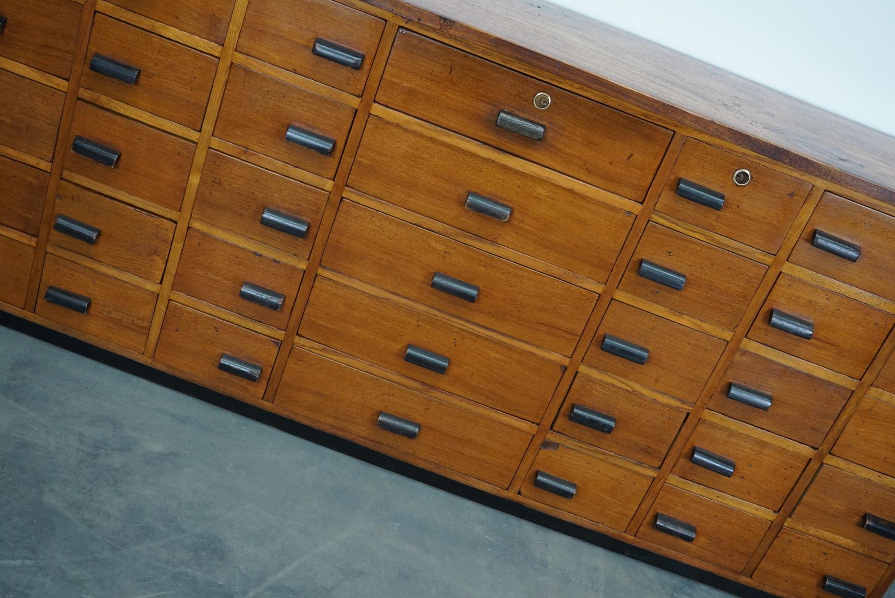 This large apothecary cabinet was made in Germany, circa 1940s. It features 35 drawers in two sizes with nice black wooden handles. It is made oak and pine and it retained a nice patina from years of use. The interior dimensions of the drawers are: